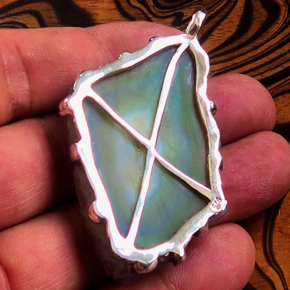 A stunning green Agate slice set in a handmade sterling silver pendant, showcasing its unique patterns and vibrant color.