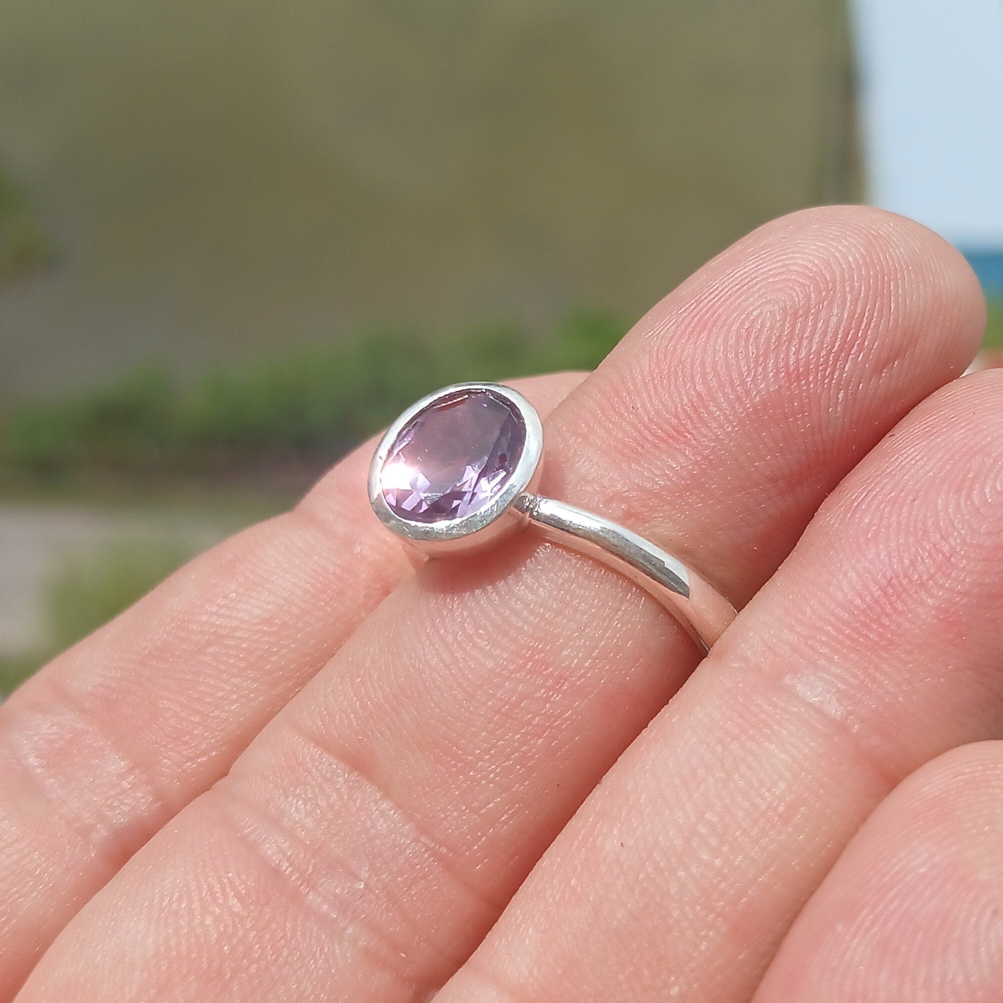 A beautiful sterling silver solitaire ring featuring a vibrant oval-shaped purple amethyst at its center, showcasing elegance and craftsmanship.