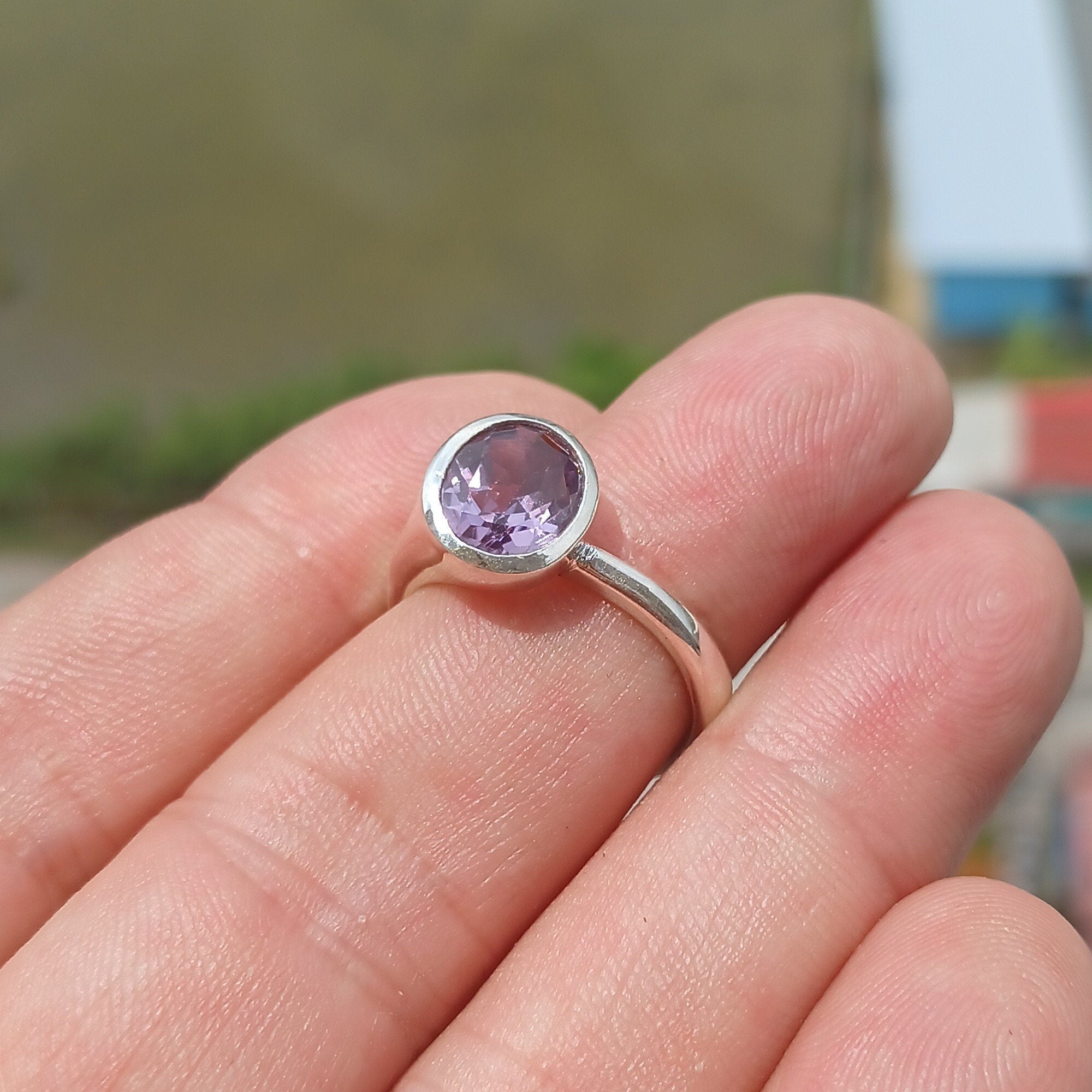 A beautiful sterling silver solitaire ring featuring a vibrant oval-shaped purple amethyst at its center, showcasing elegance and craftsmanship.