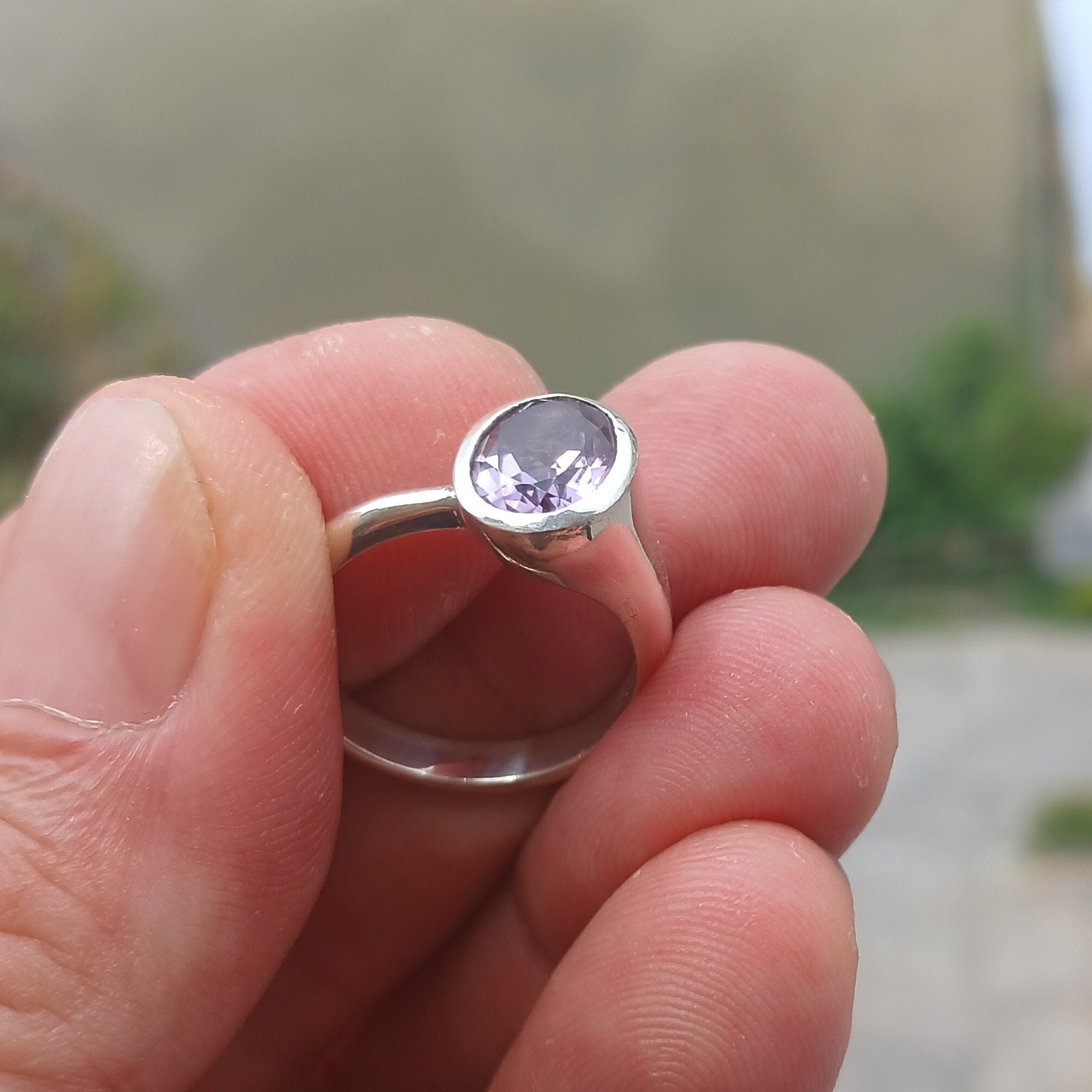 A beautiful sterling silver solitaire ring featuring a vibrant oval-shaped purple amethyst at its center, showcasing elegance and craftsmanship.