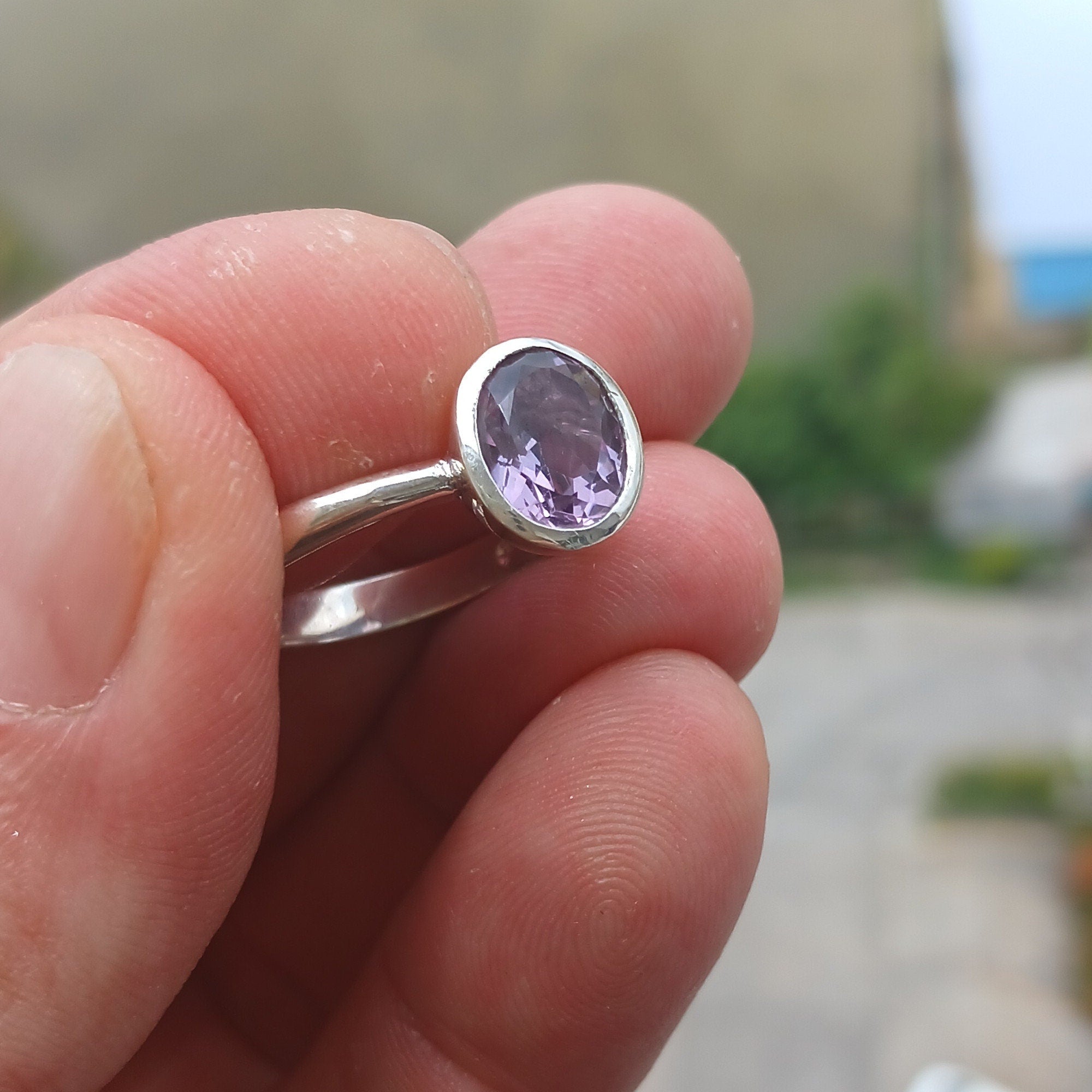 A beautiful sterling silver solitaire ring featuring a vibrant oval-shaped purple amethyst at its center, showcasing elegance and craftsmanship.