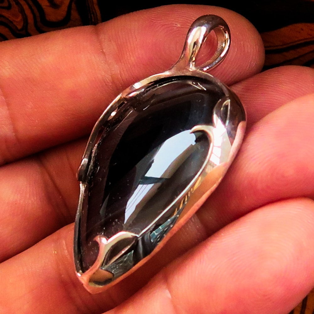 A stunning Black Agate Pendant featuring a floral design in sterling silver, showcasing a black Agate cabochon at its center.