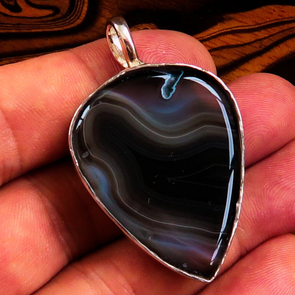 A stunning Black Agate Pendant featuring a floral design in sterling silver, showcasing a black Agate cabochon at its center.