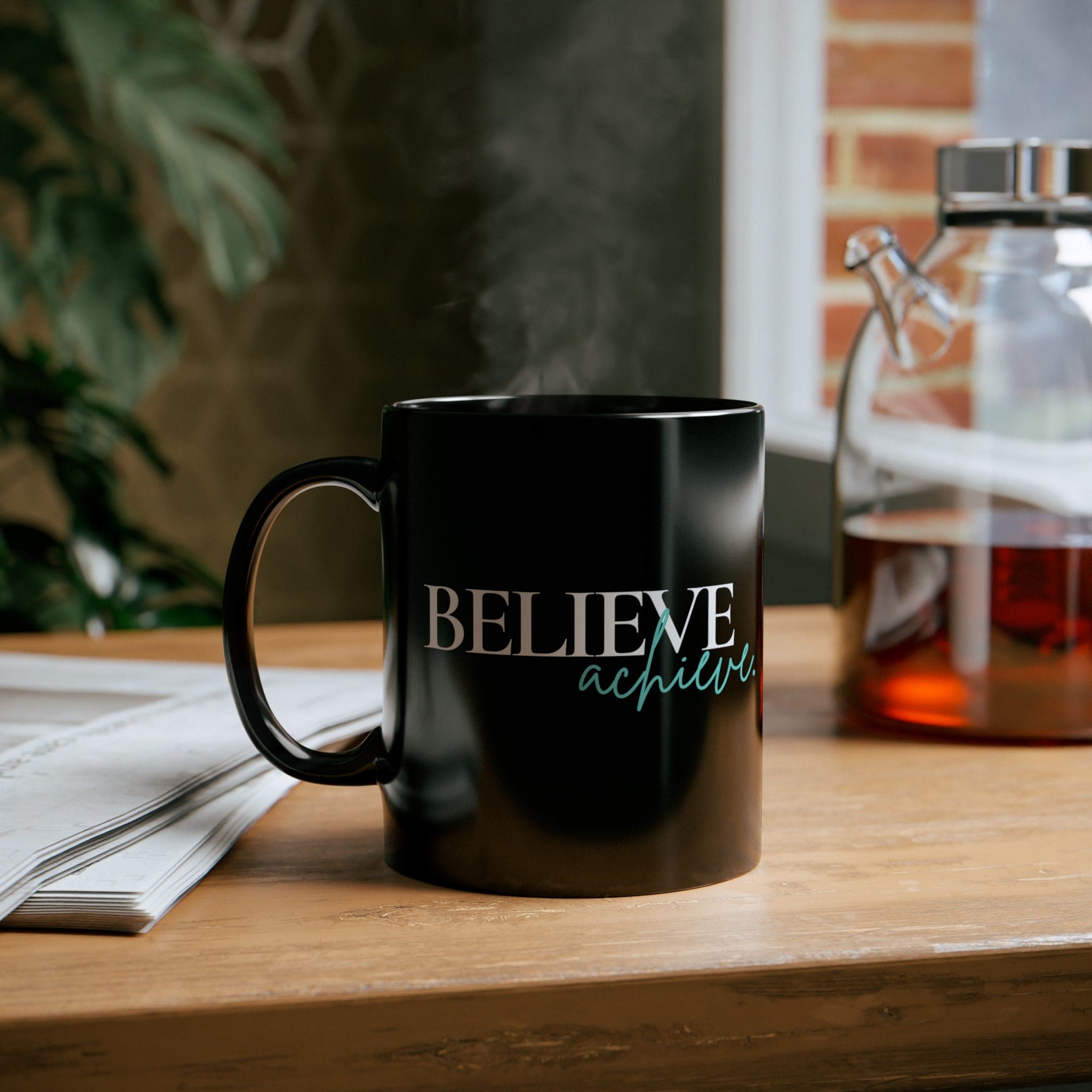 A sleek black ceramic mug with a glossy finish, featuring the inspirational phrase 'Believe and Achieve' on the side, perfect for coffee or tea.