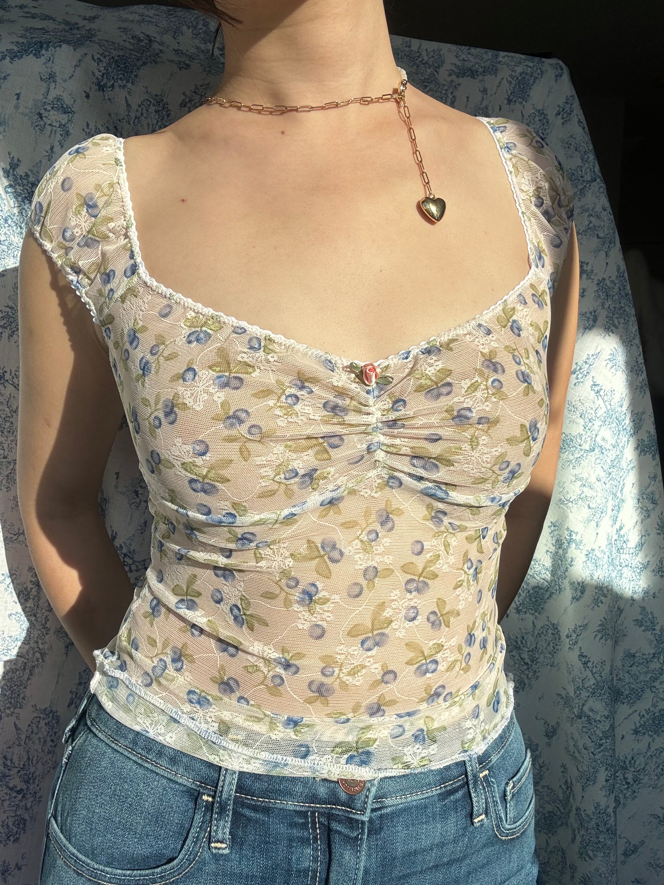 A stylish blue cherry print top featuring delicate lacework and cami straps, perfect for casual and semi-formal occasions.