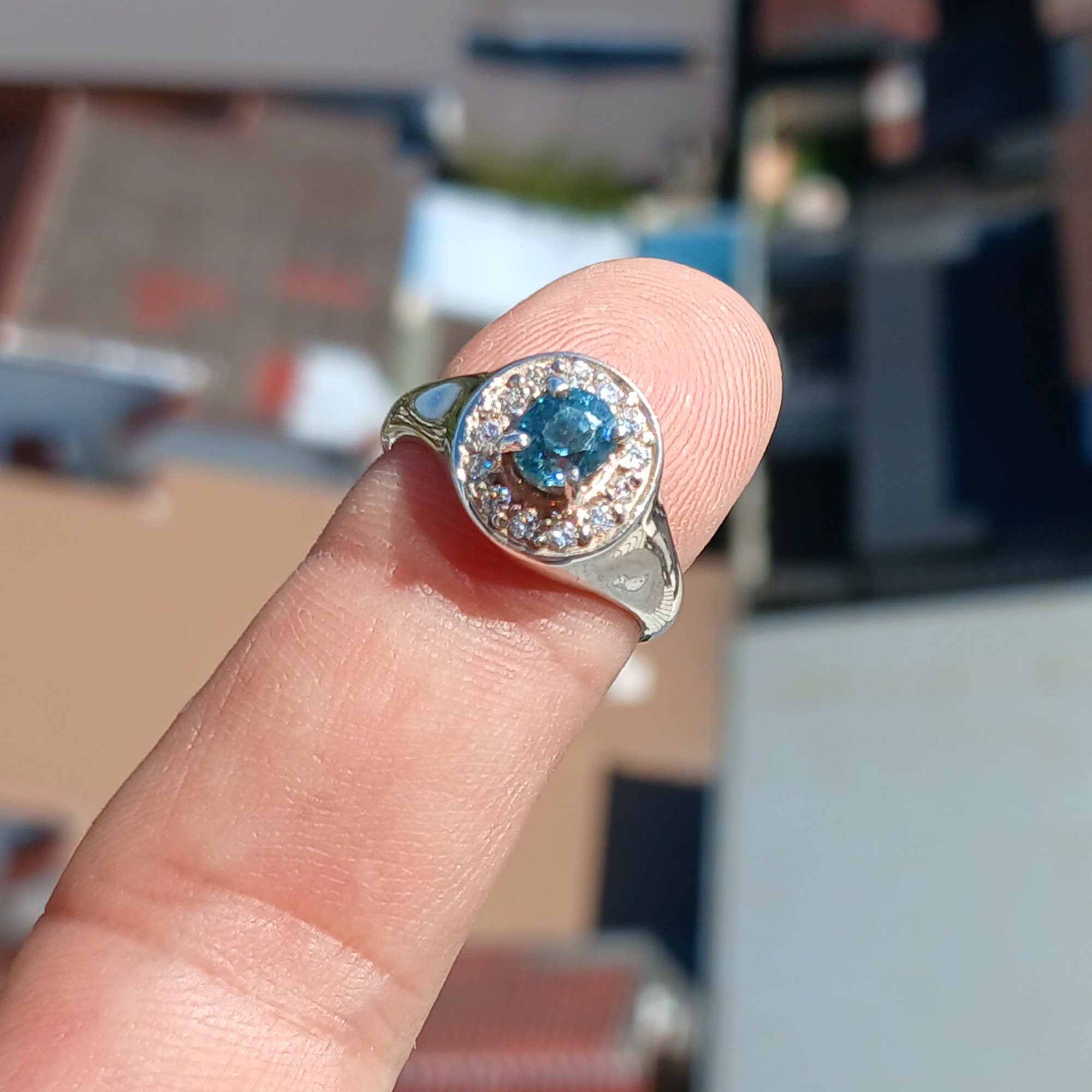 Elegant Blue Zircon Ring featuring a natural blue Zircon stone surrounded by white CZ stones in polished sterling silver.