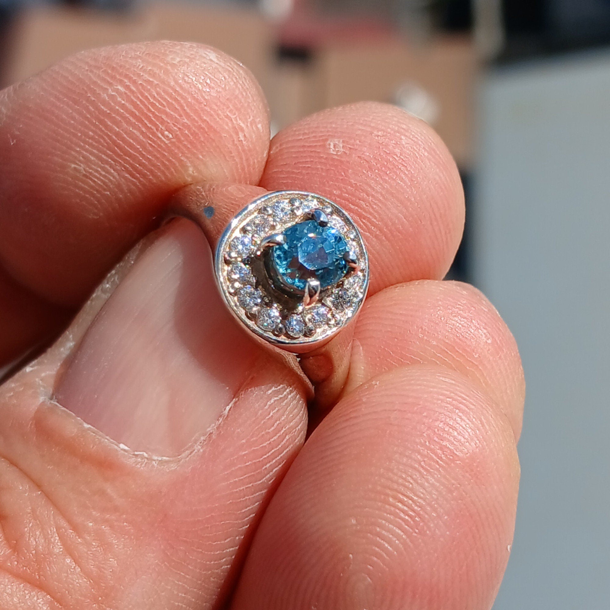 Elegant Blue Zircon Ring featuring a natural blue Zircon stone surrounded by white CZ stones in polished sterling silver.