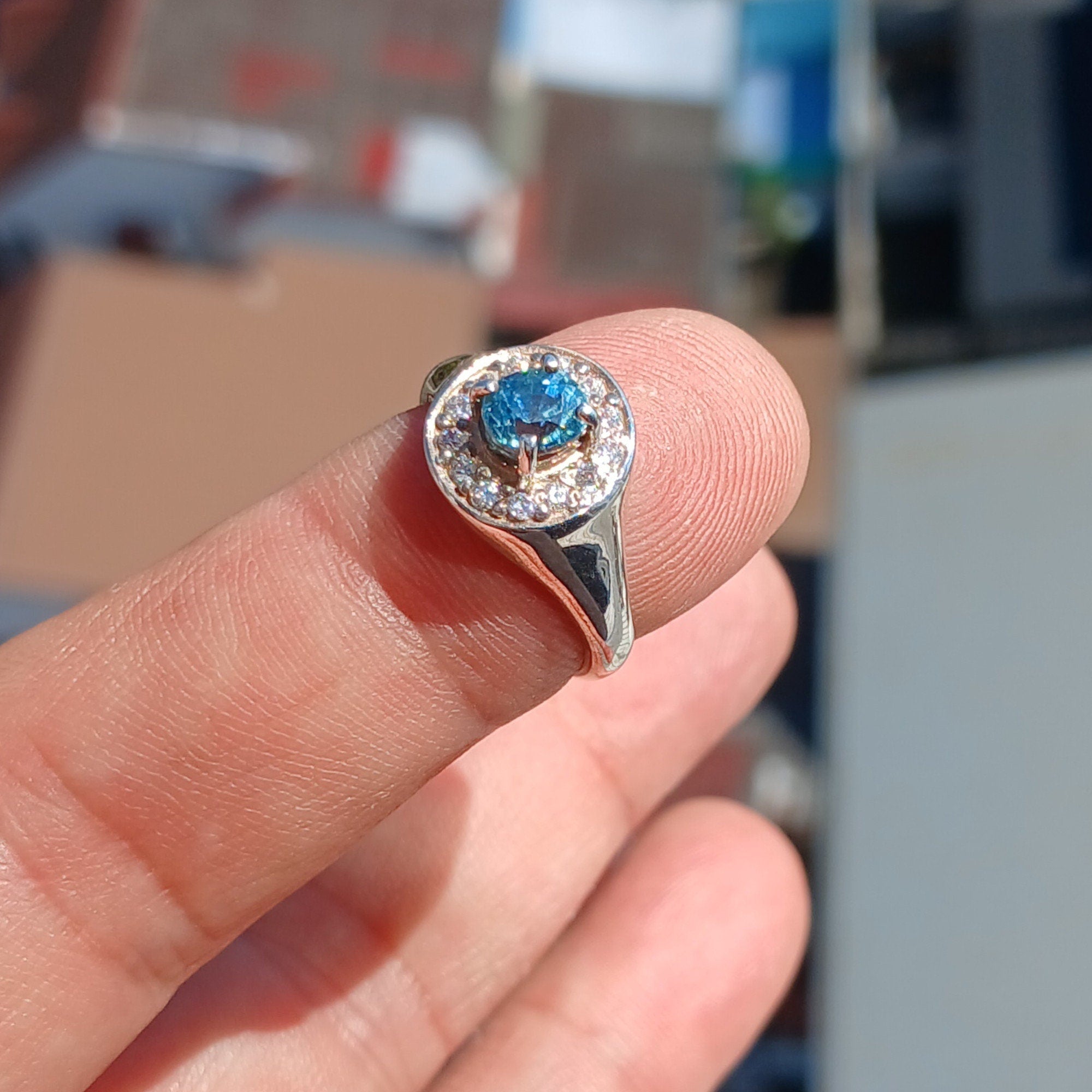 Elegant Blue Zircon Ring featuring a natural blue Zircon stone surrounded by white CZ stones in polished sterling silver.