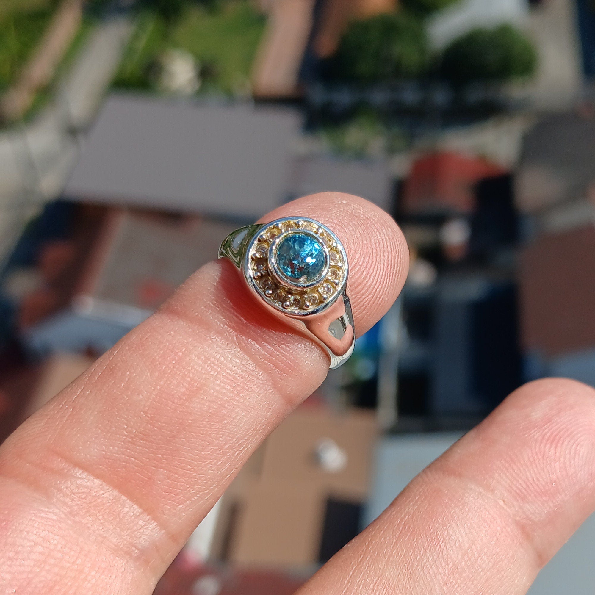 A polished sterling silver ring featuring a round cut blue zircon gemstone, showcasing its vibrant color and elegant design.