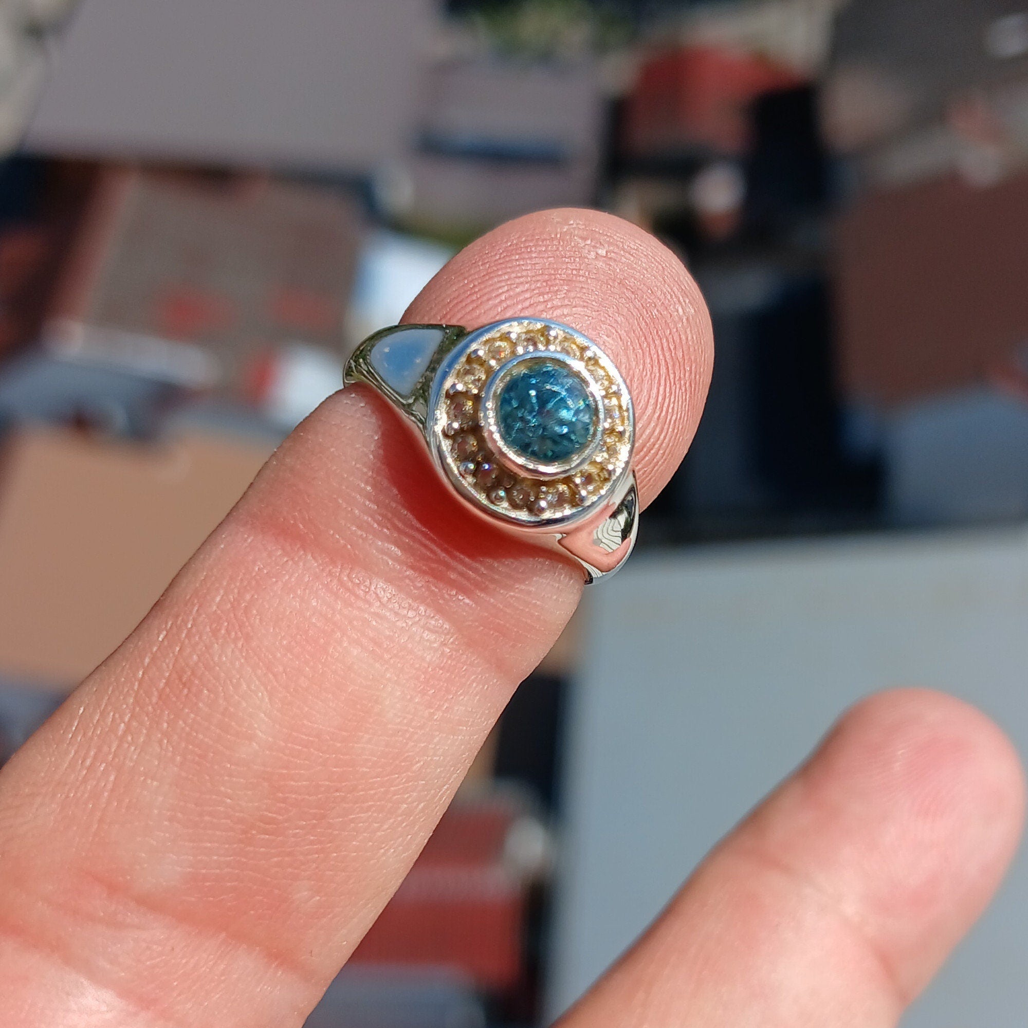 A polished sterling silver ring featuring a round cut blue zircon gemstone, showcasing its vibrant color and elegant design.