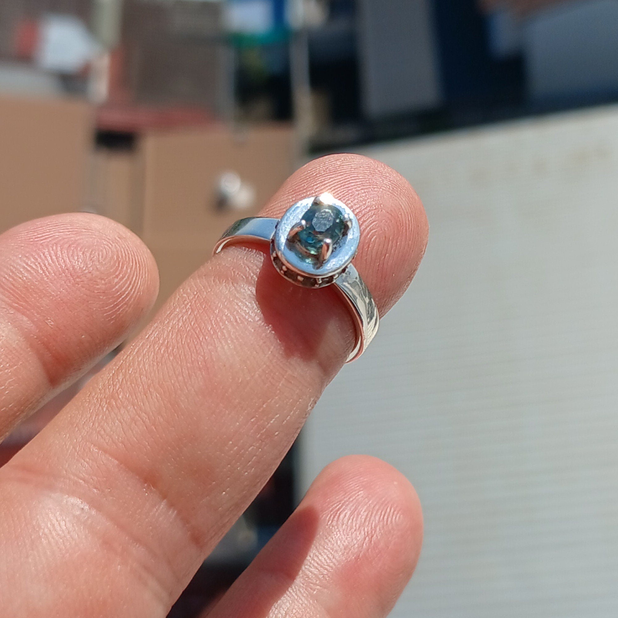 A stunning Blue Zircon Ring featuring an oval cut blue zircon centerpiece surrounded by 14 white CZ stones, set in a polished sterling silver band.