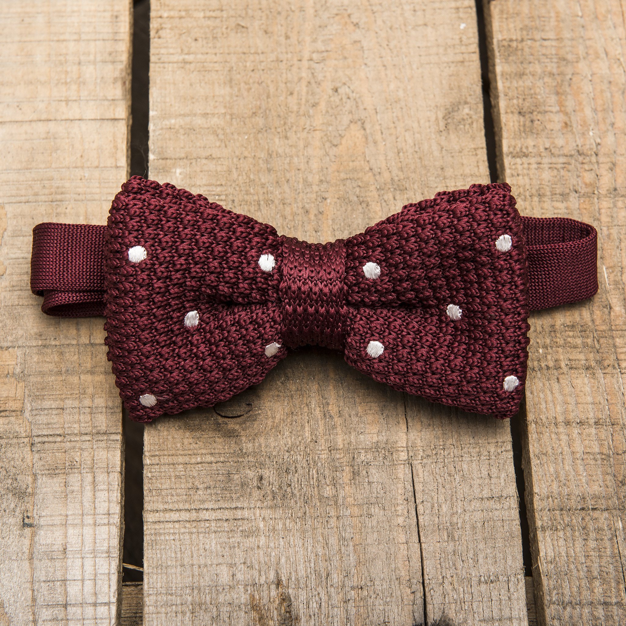 Burgundy and white spotted bow tie made of polyester, featuring a classic design suitable for various occasions.