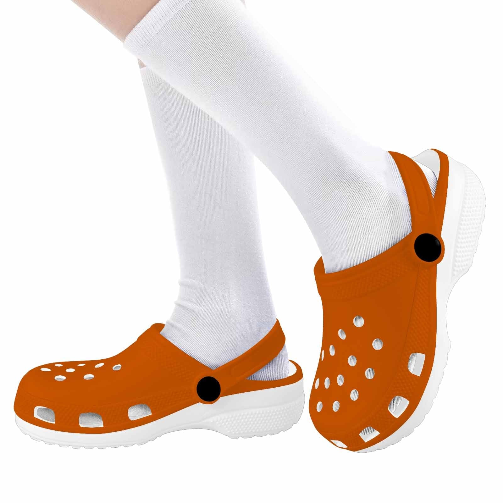 A pair of burnt orange clogs designed for youth, featuring a slip-on design, ventilation ports, and cushioned soles for comfort.