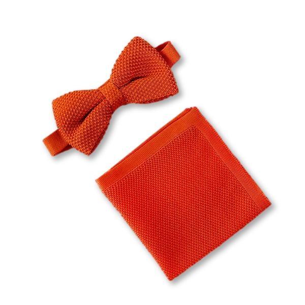 Burnt orange knitted bow tie and matching pocket square set displayed elegantly, showcasing their vibrant color and texture.