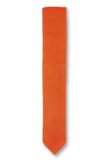 Burnt orange knitted tie with a pointed end, showcasing its texture and vibrant color.