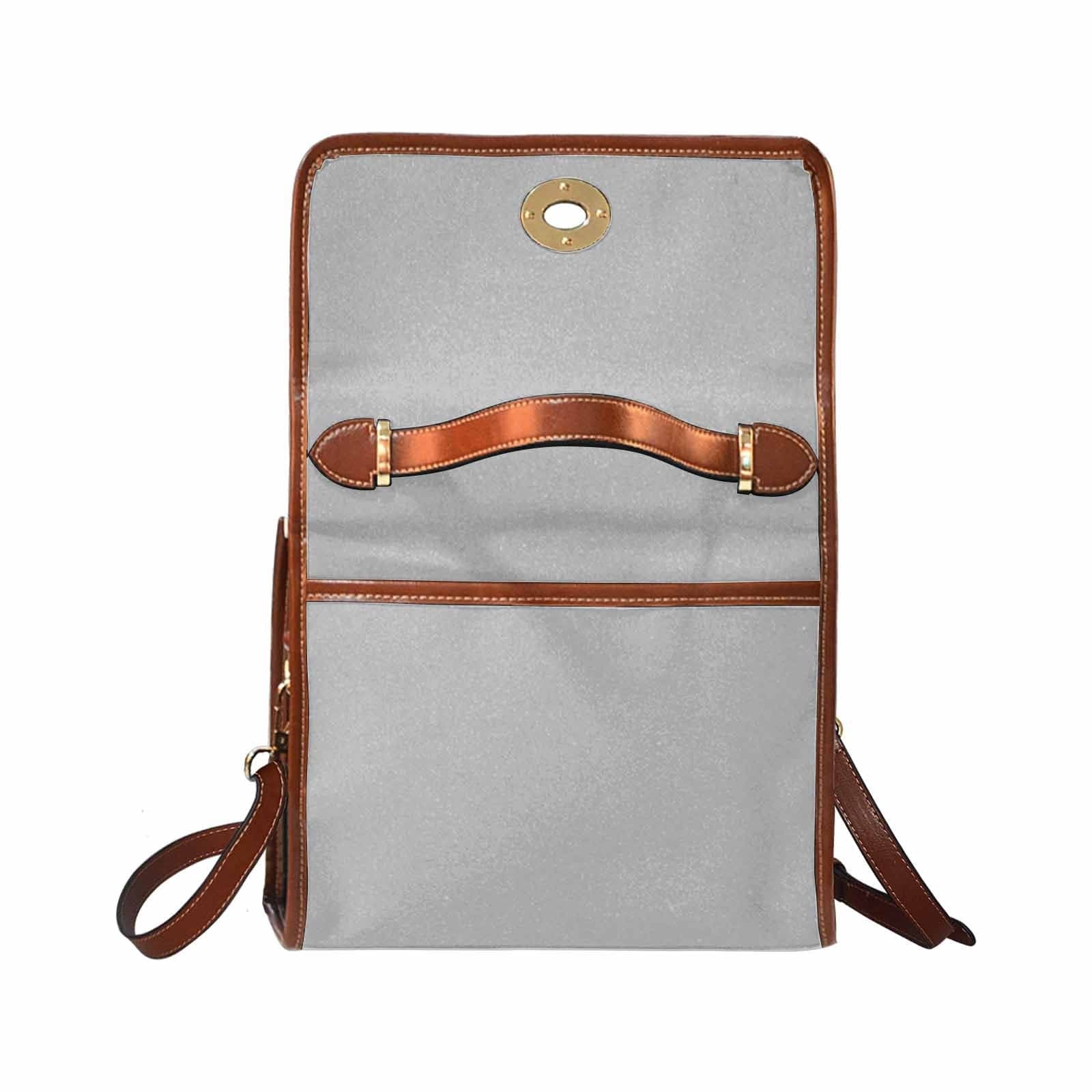 Light grey canvas bag with brown strap, featuring two interior pockets and a zipper pocket, ideal for versatile use.