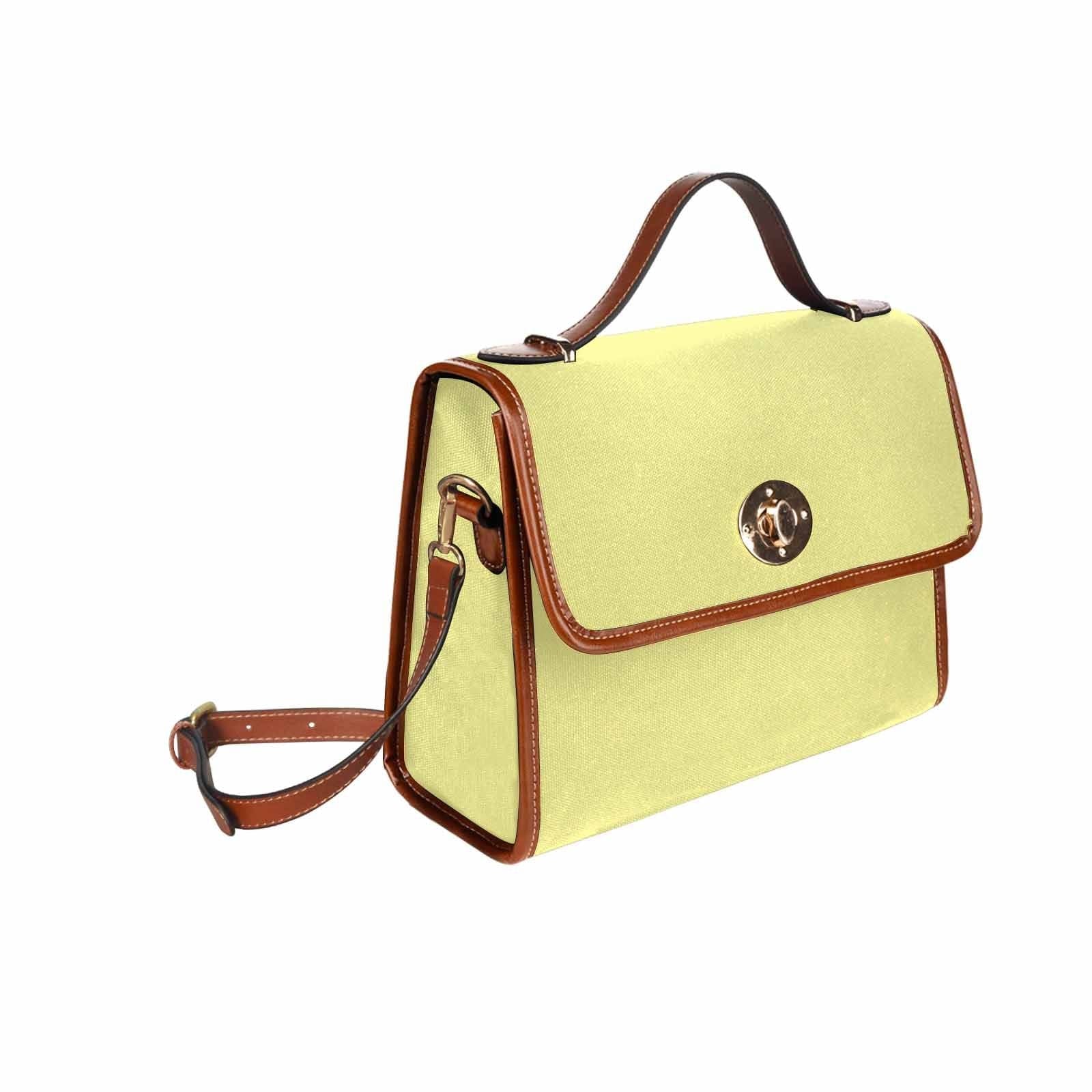 Pastel yellow canvas handbag with a brown crossbody strap, featuring two interior pockets and a zipper pocket.