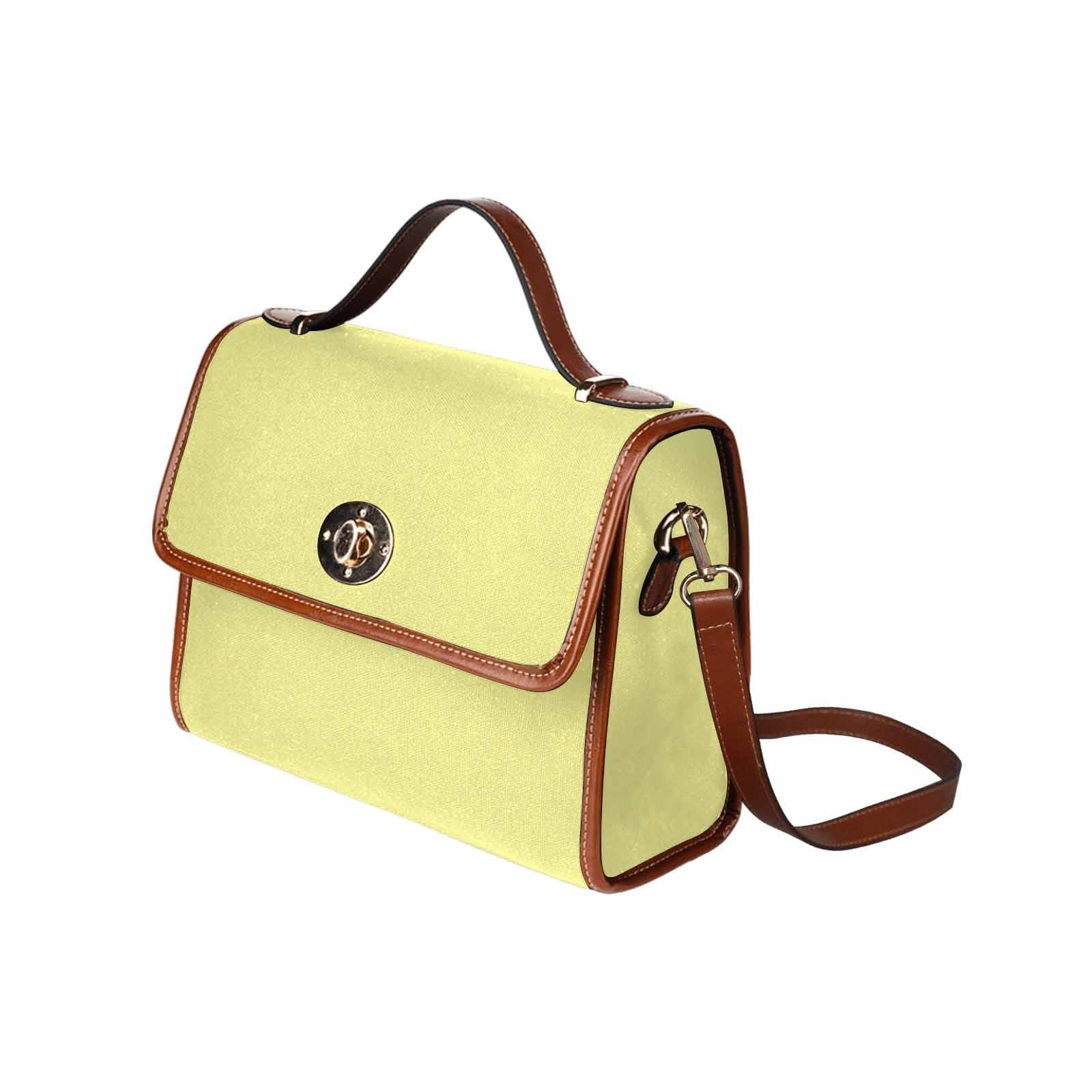 Pastel yellow canvas handbag with a brown crossbody strap, featuring two interior pockets and a zipper pocket.