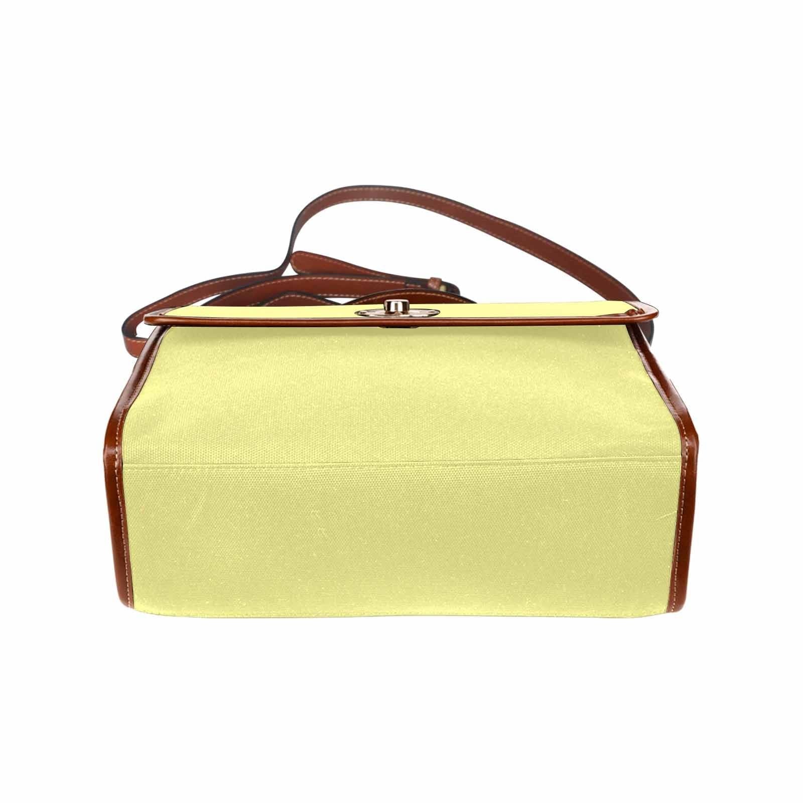 Pastel yellow canvas handbag with a brown crossbody strap, featuring two interior pockets and a zipper pocket.