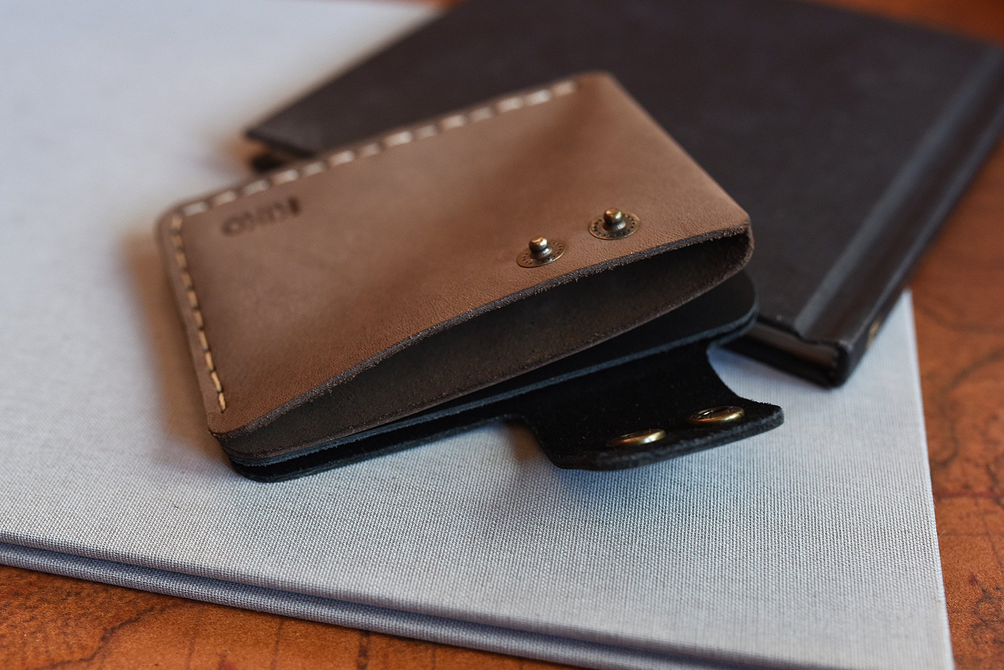 A stylish Card Wallet made of smooth leather, featuring a button flap closure and artisan stitching, perfect for holding cards and cash.