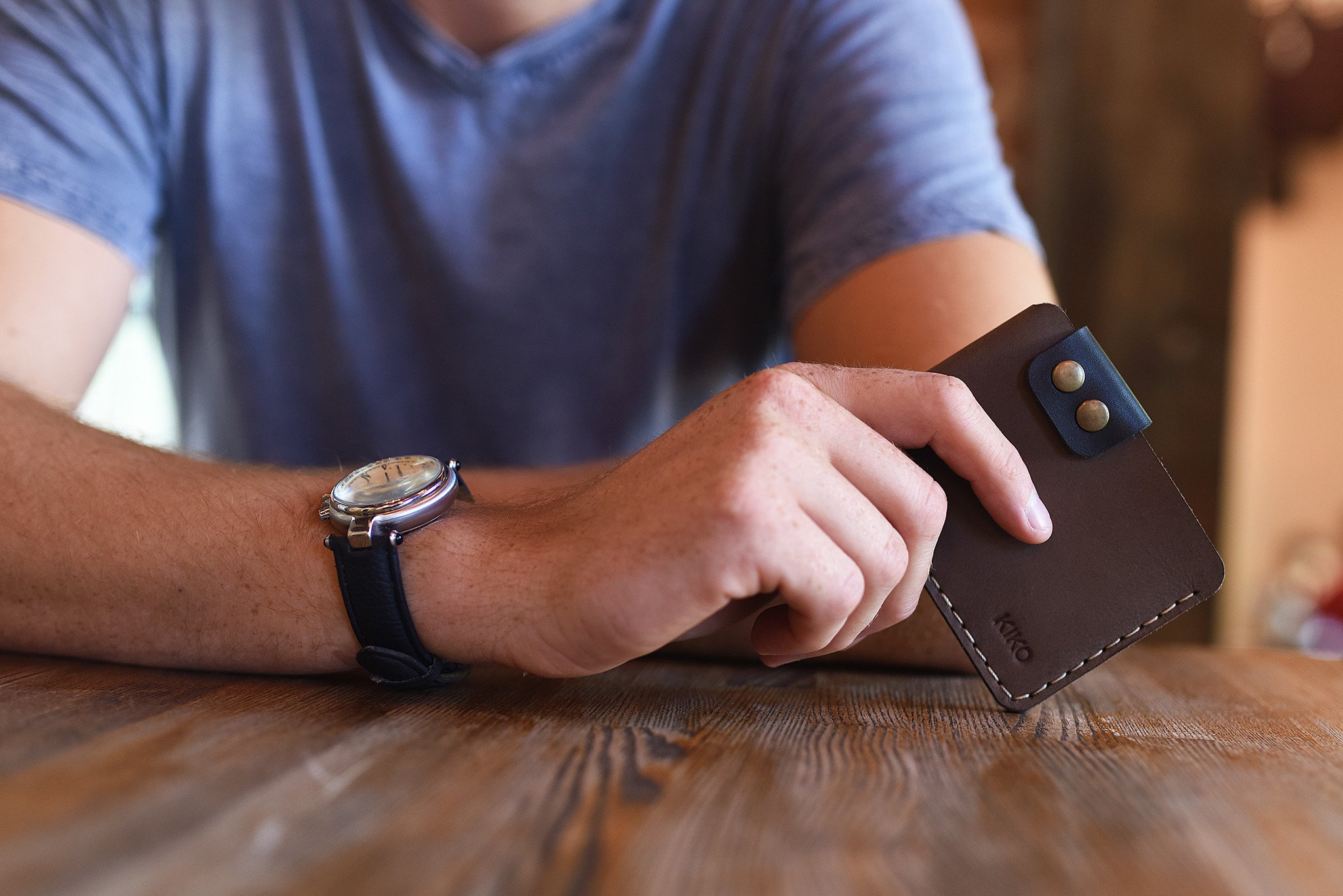 A stylish Card Wallet made of smooth leather, featuring a button flap closure and artisan stitching, perfect for holding cards and cash.