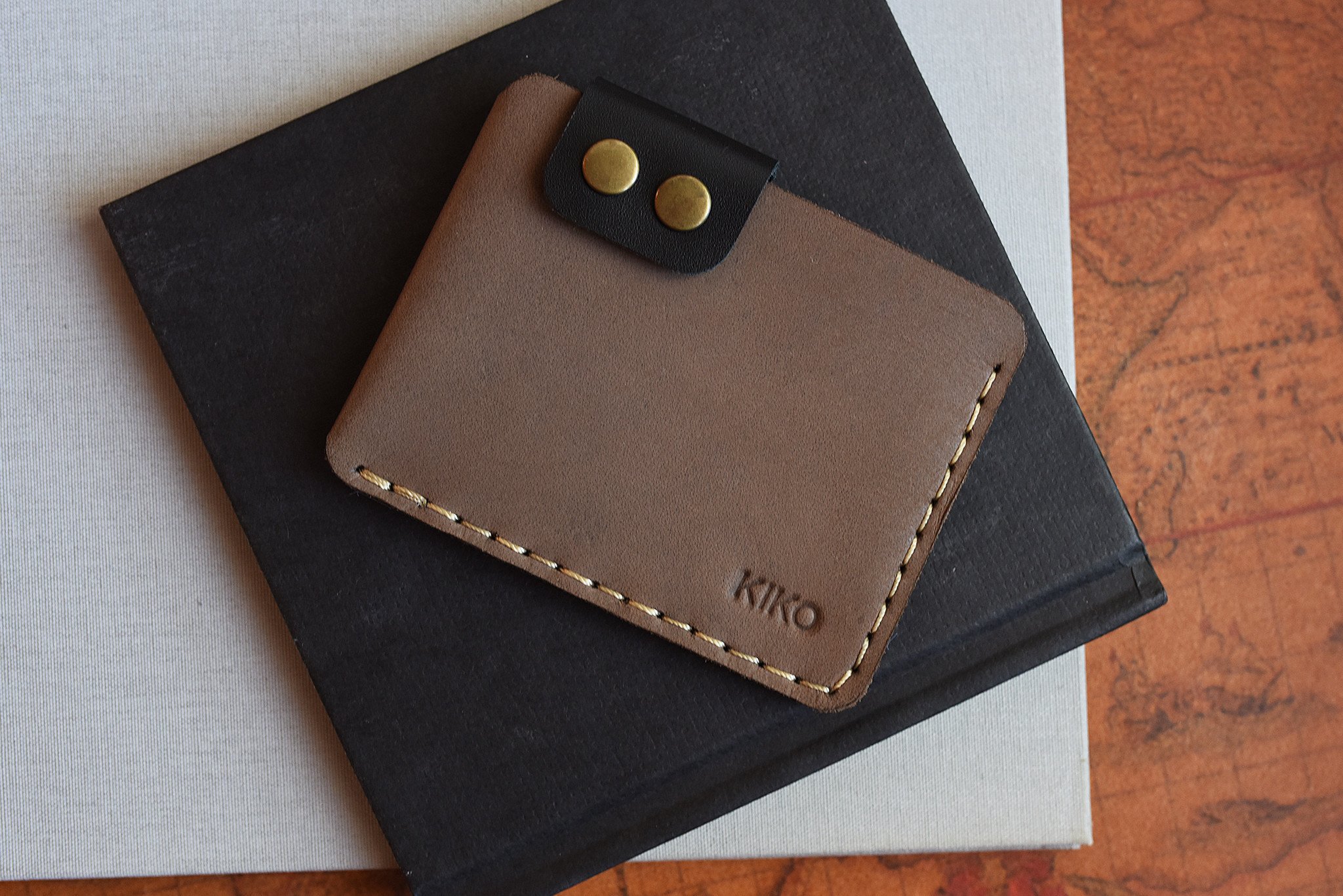 A stylish Card Wallet made of smooth leather, featuring a button flap closure and artisan stitching, perfect for holding cards and cash.