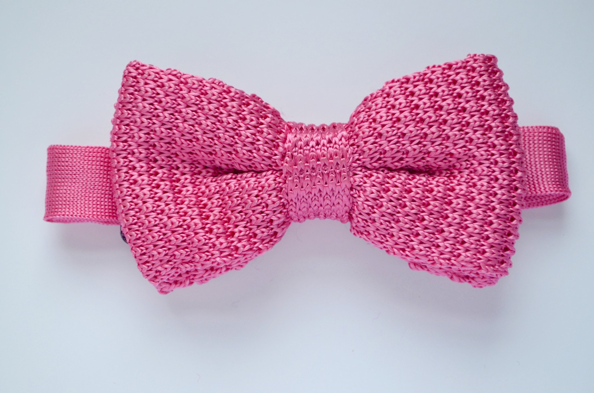 A deep pink handmade silk knitted bow tie for children, pre-tied and perfect for special occasions.