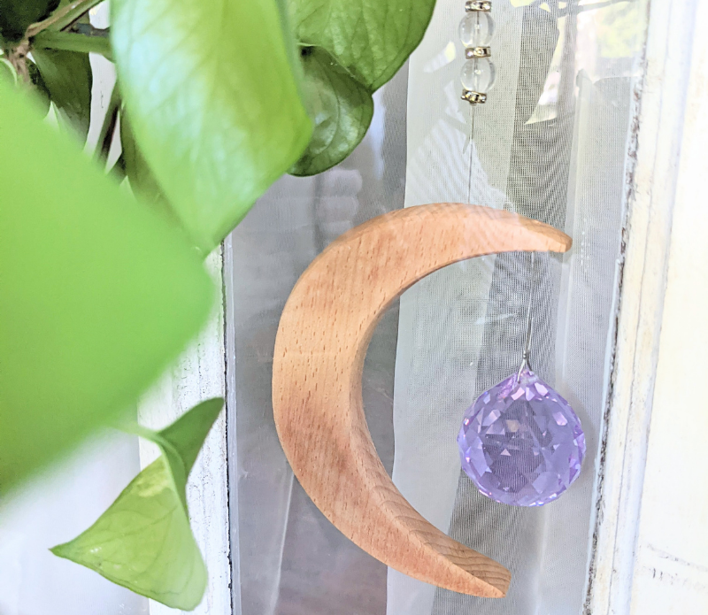 Crescent Moon Rainbow Maker featuring a purple prism and wooden crescent moon with 'Shine your Light' inscription, hanging in a sunlit window.