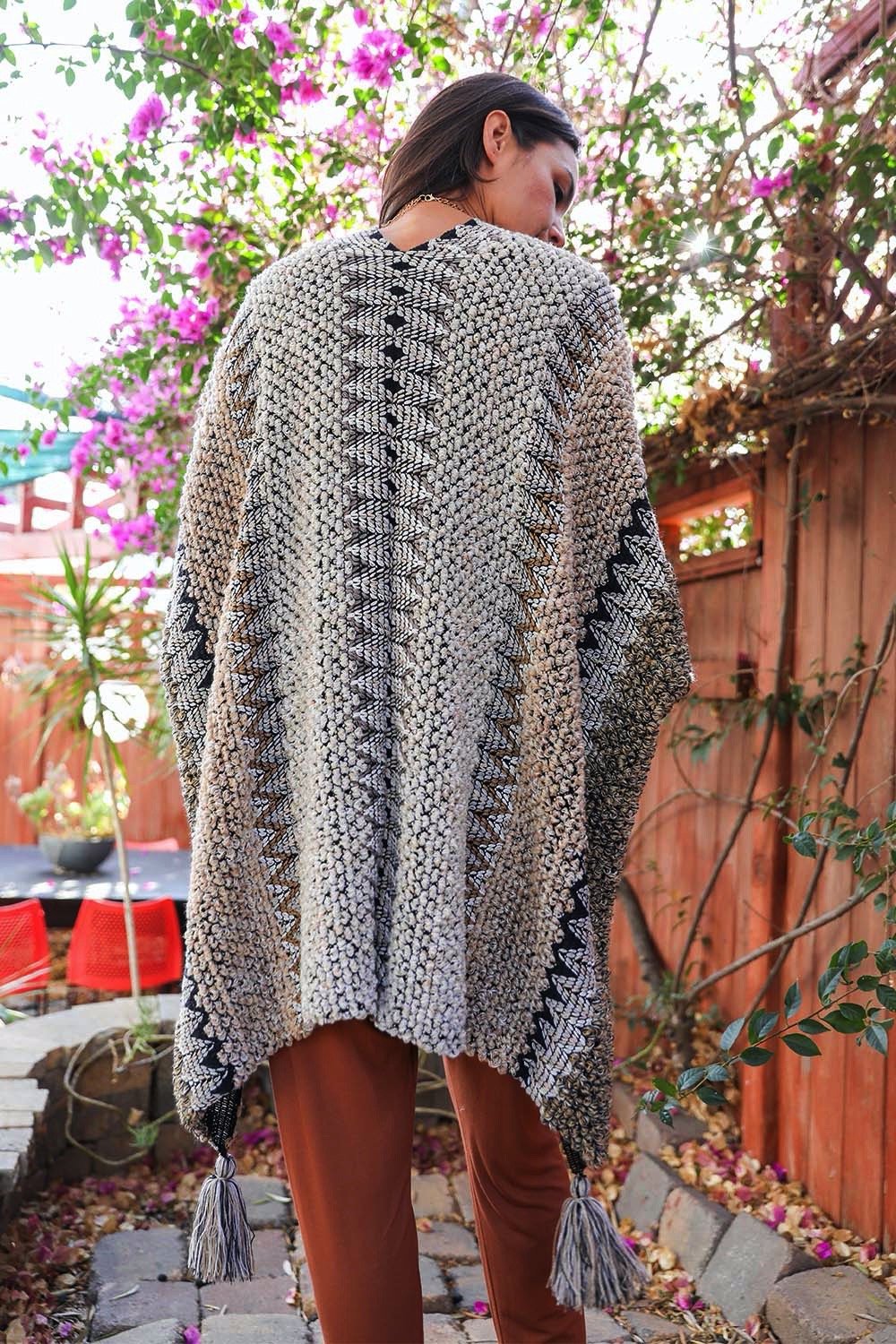 A cozy crochet patterned ruana with tassels, showcasing a boho-chic style, perfect for chilly weather.