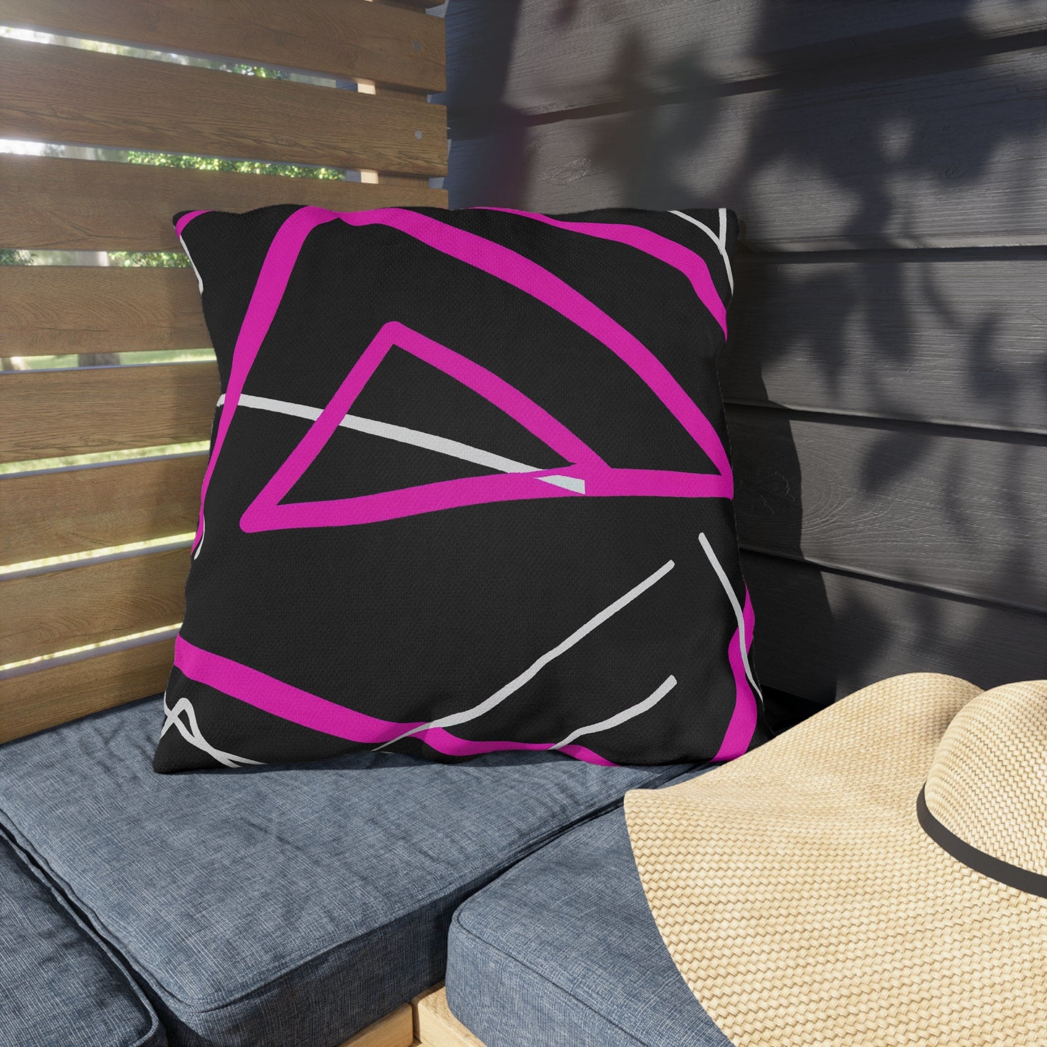 Decorative indoor/outdoor pillow featuring a black and pink geometric pattern, showcasing vibrant colors and unique design.