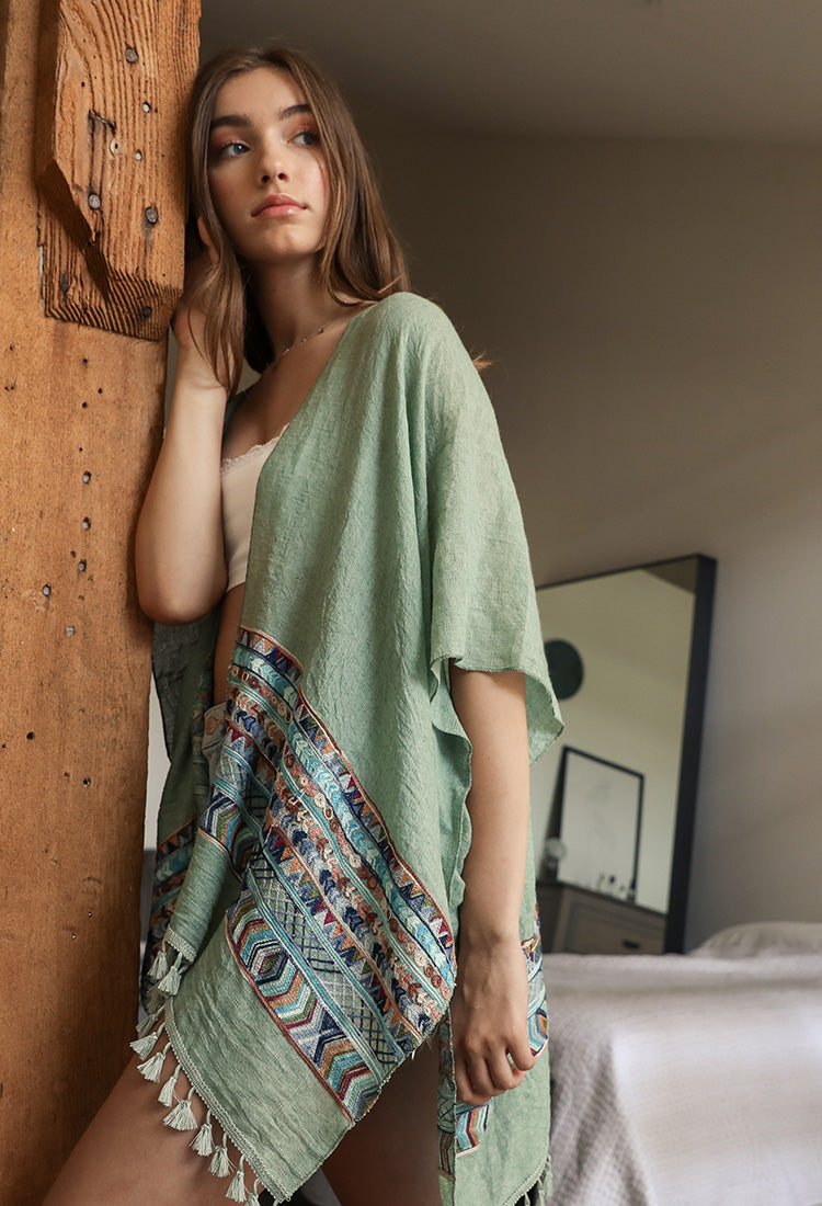 A lightweight linen kimono featuring a vibrant geometric embroidery pattern, perfect for layering or as a swimsuit cover-up.