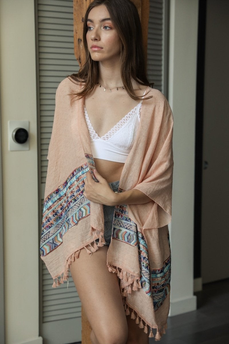 A lightweight linen kimono featuring a vibrant geometric embroidery pattern, perfect for layering or as a swimsuit cover-up.