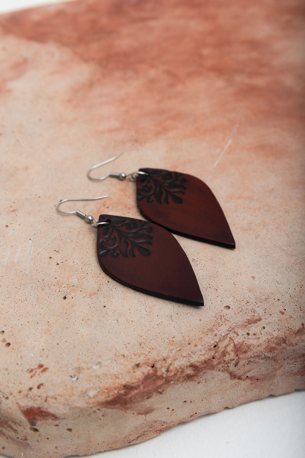 A pair of Engraved Leaf Leather Earrings showcasing intricate leaf designs on soft genuine leather, perfect for stylish outfits.