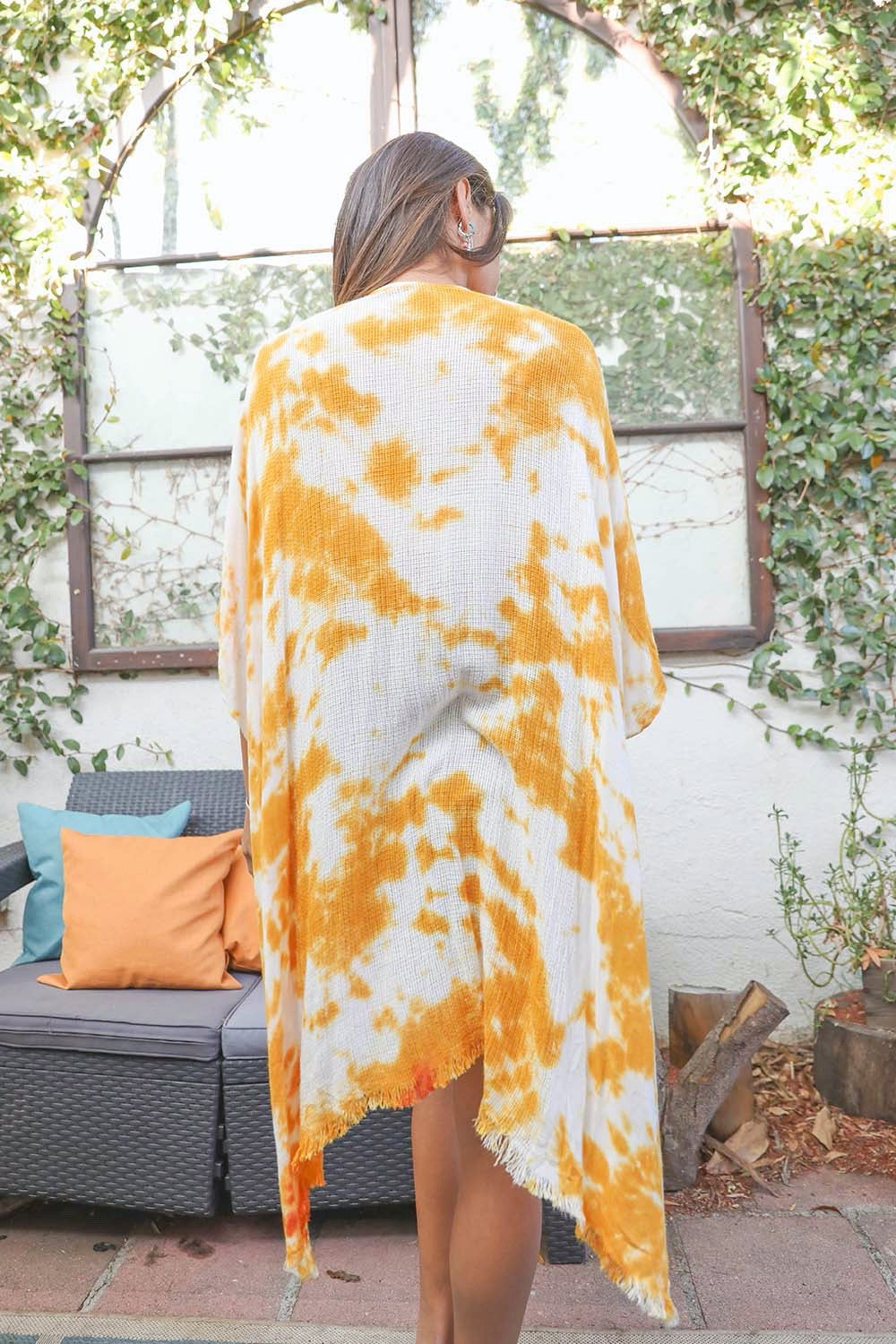 A colorful tie-dye kimono with vibrant patterns, perfect for festivals and warm weather, draped elegantly on a mannequin.