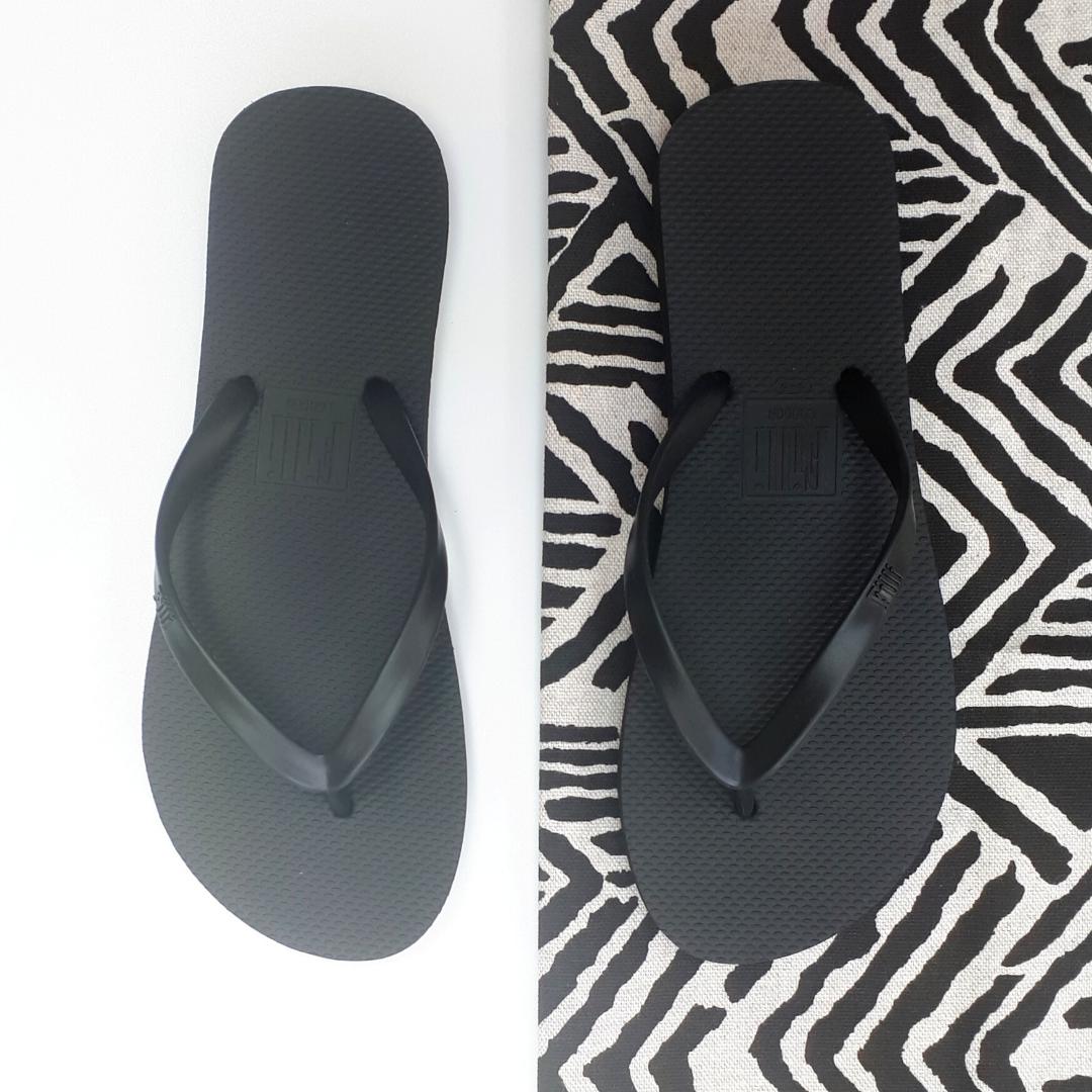 Filli London Naked Flip Flops in Black with embossed logo and smooth strap, displayed in a cotton drawstring bag.