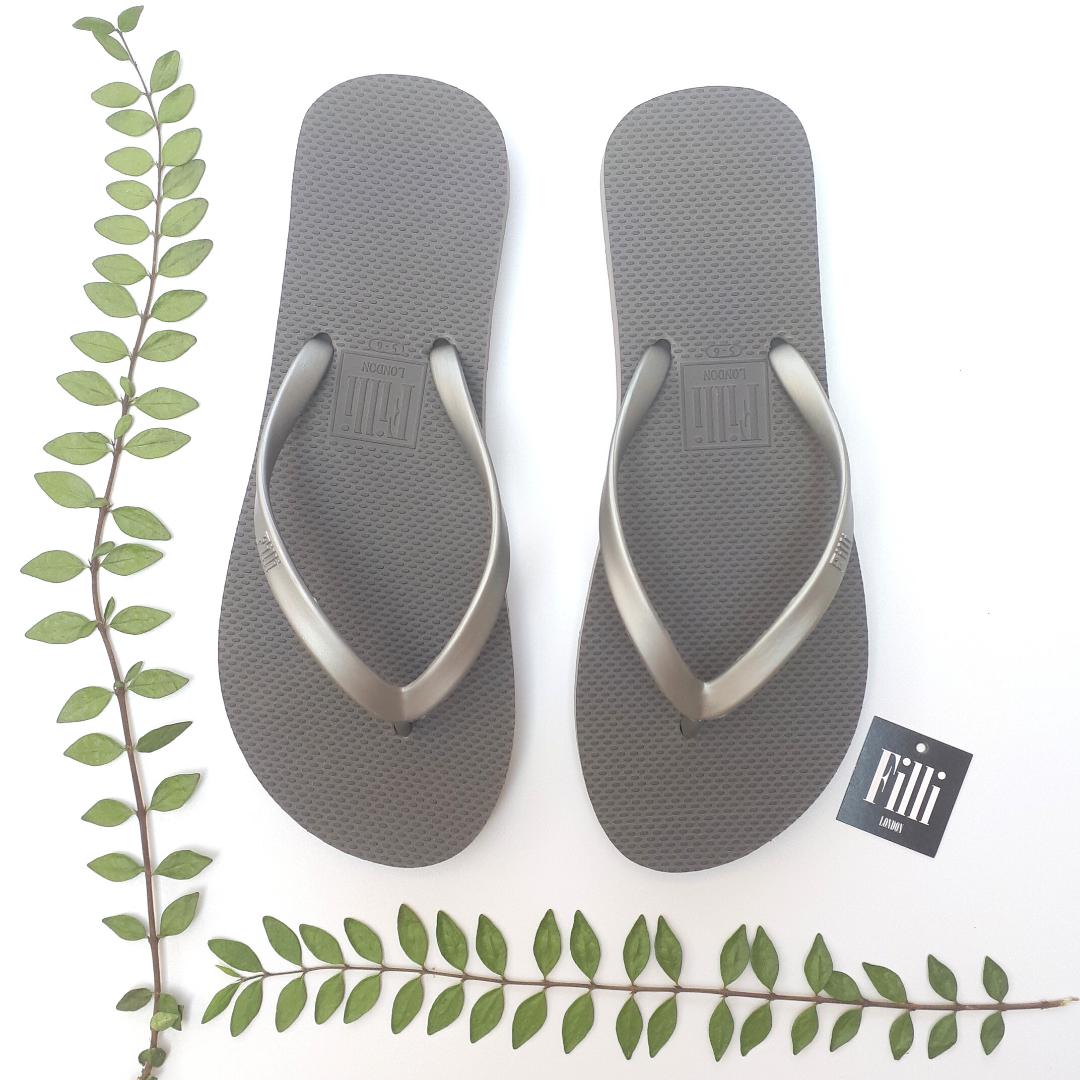 Filli London Naked Flip Flops in Silver with embossed logo and smooth strap, displayed in a cotton drawstring bag.