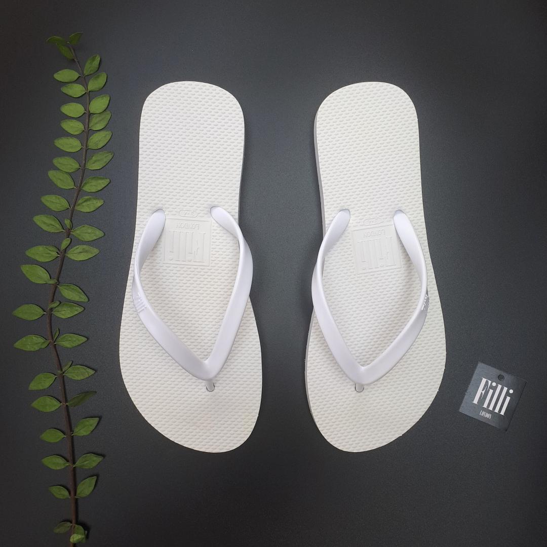 Filli London Naked Flip Flops in White with embossed sole and smooth strap, displayed in a cotton drawstring bag.