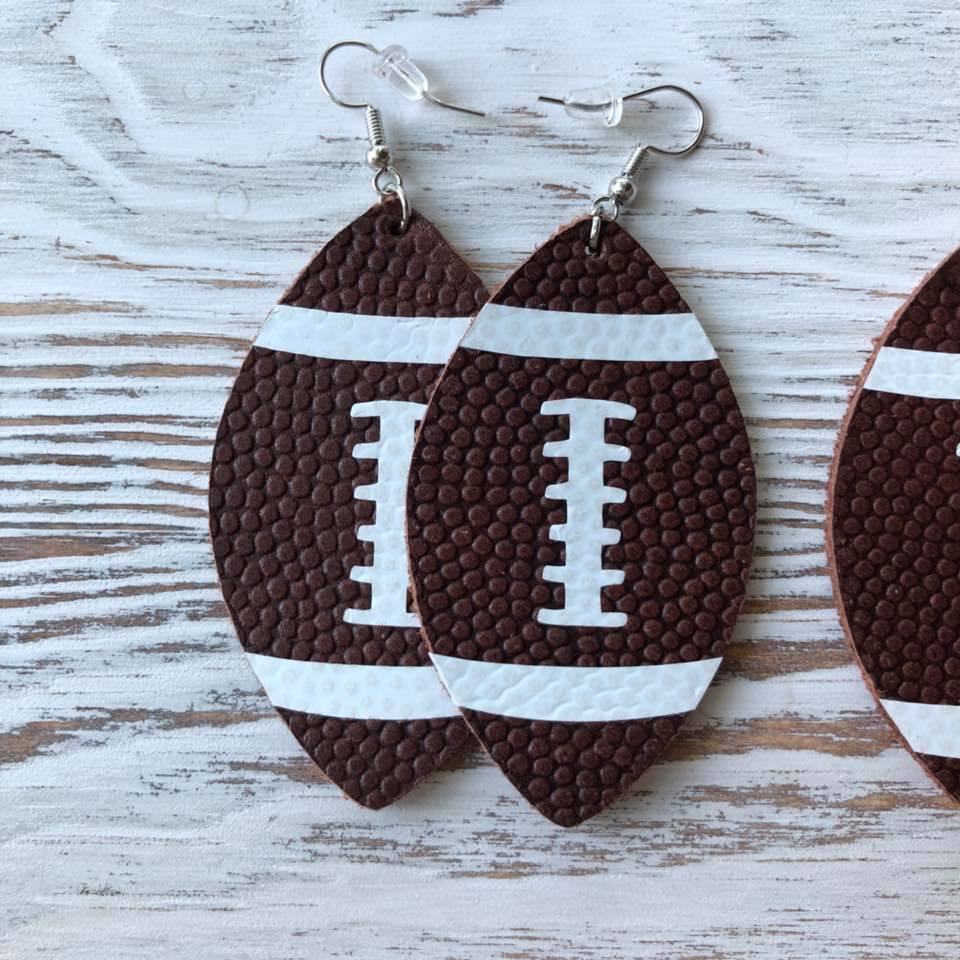 A pair of stylish football-shaped leather hang earrings, measuring 2.5 inches, showcasing a unique design perfect for sports enthusiasts.