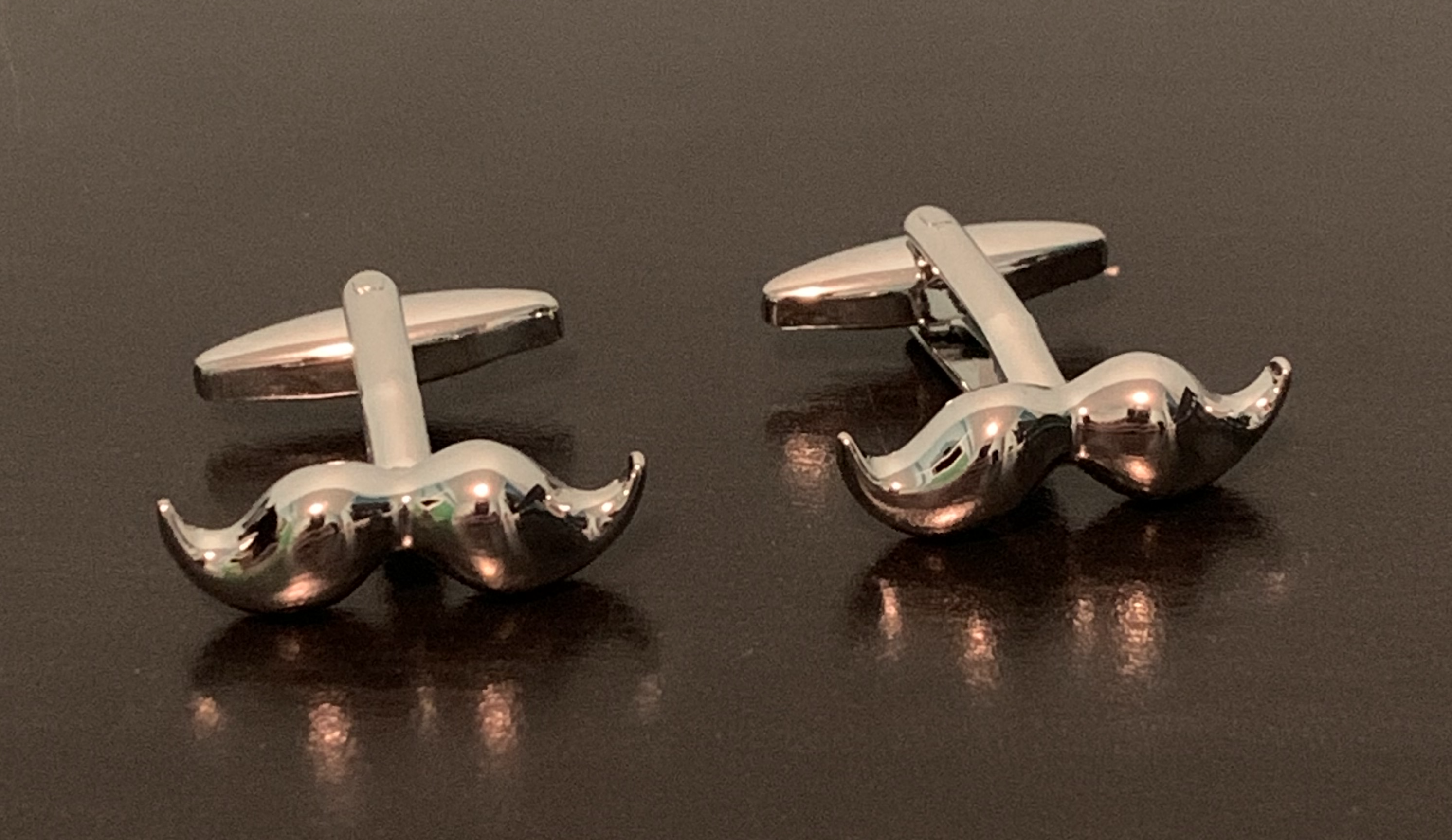 Polished silver cufflinks featuring a unique moustache design, perfect for stylish gentlemen.