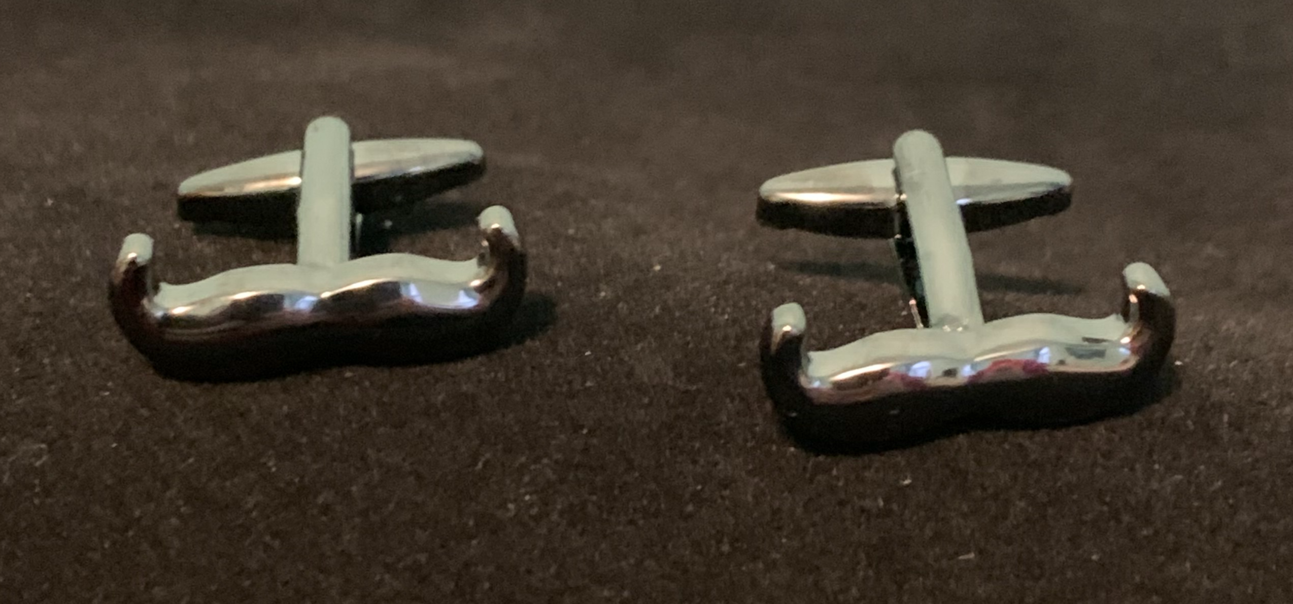 Polished silver cufflinks featuring a unique moustache design, perfect for stylish gentlemen.