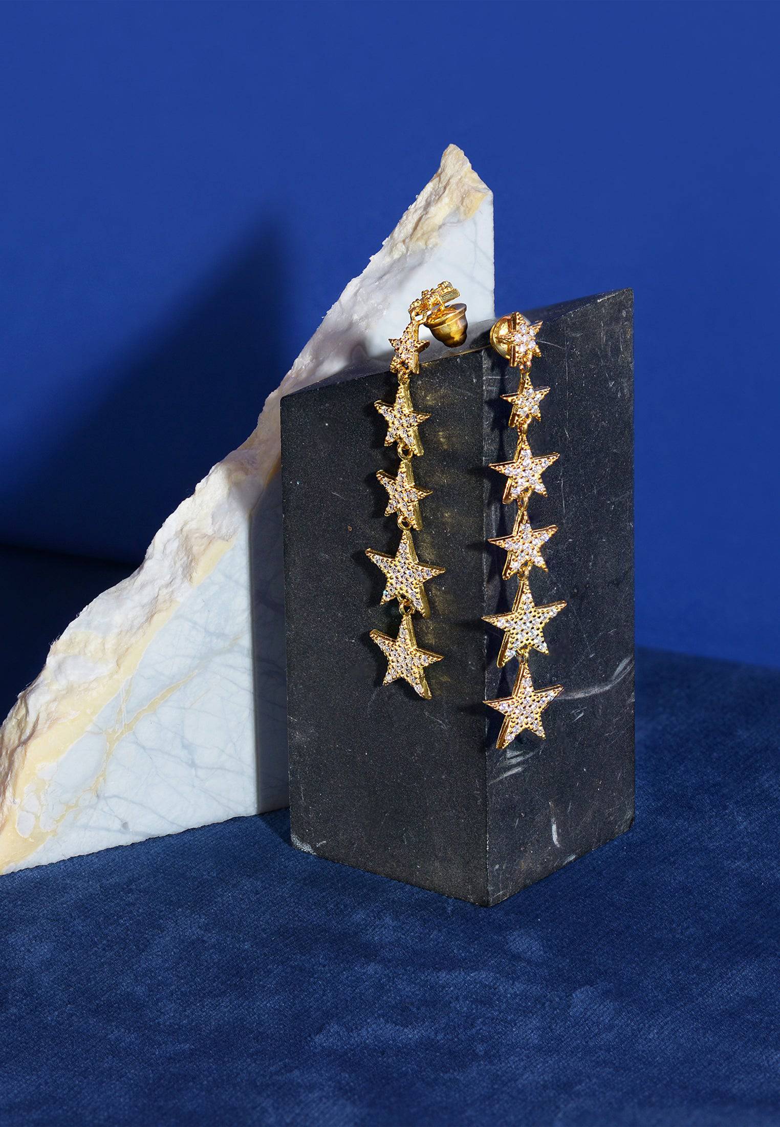 A pair of elegant graduated star drop earrings in gold, featuring six stars adorned with sparkling zircon detailing, hanging gracefully.