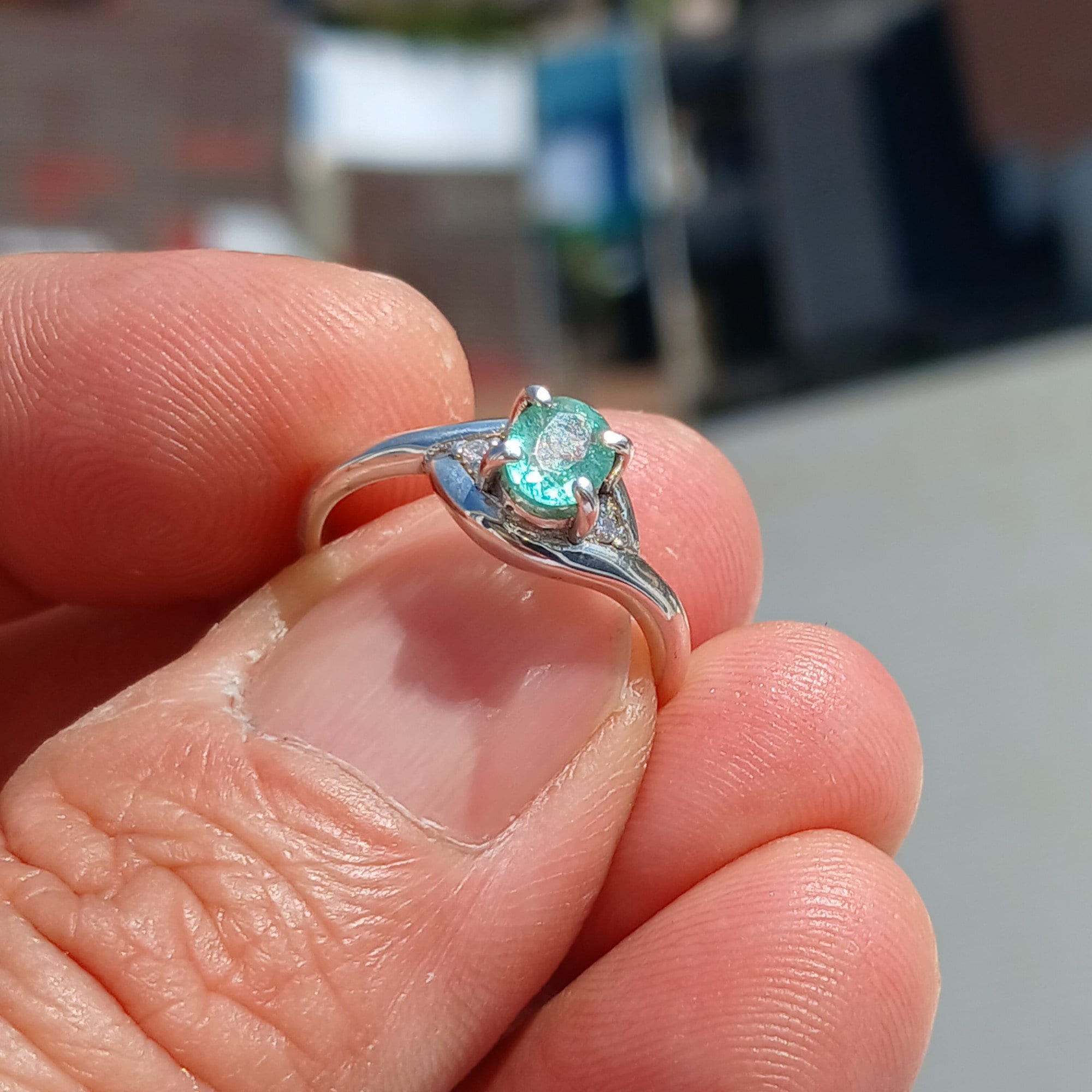 A stunning Green Emerald Ring featuring a natural oval cut emerald set in a polished sterling silver band with cubic zirconia accents.