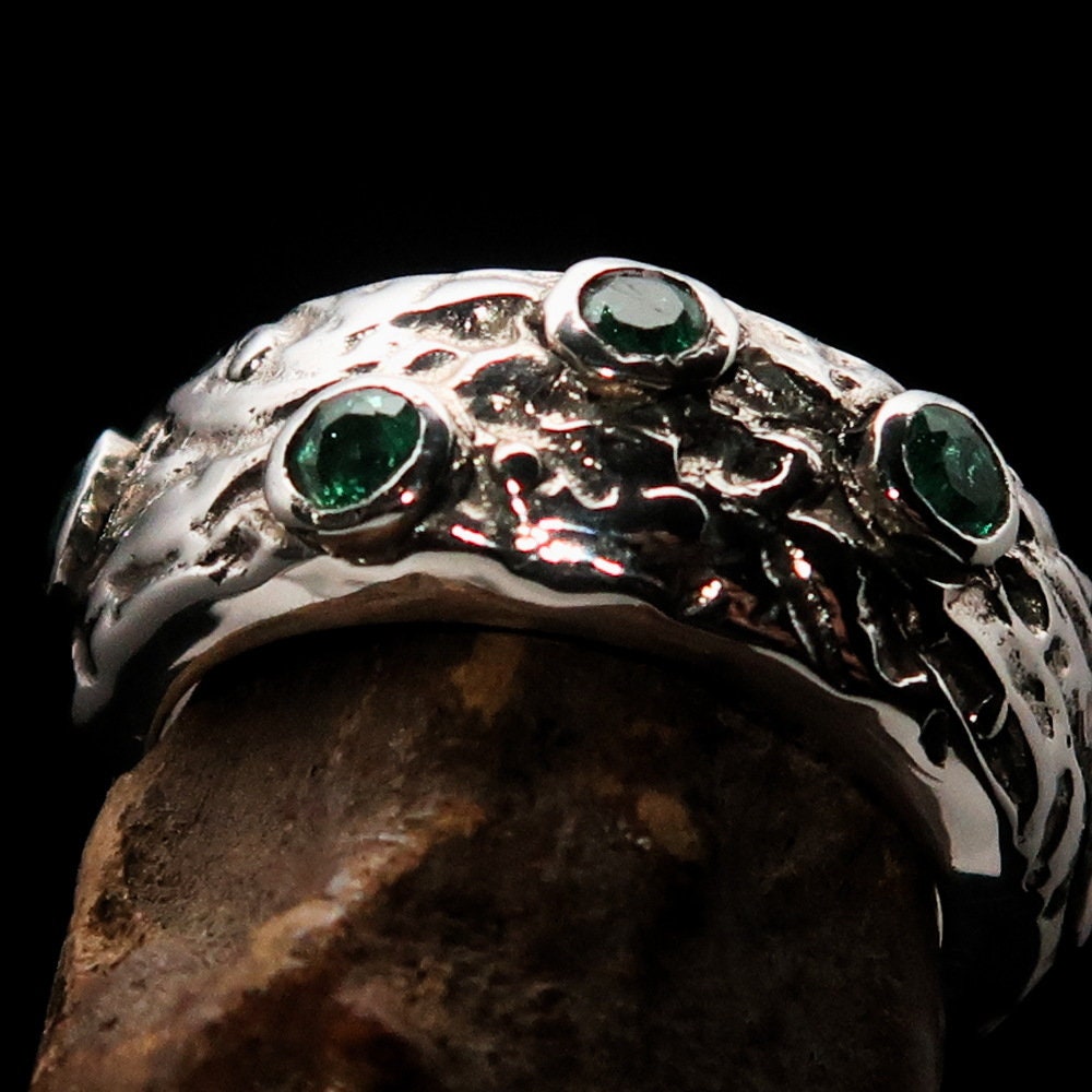 A stunning handmade green emerald ring featuring 11 irregular settings of emeralds in a polished sterling silver band.