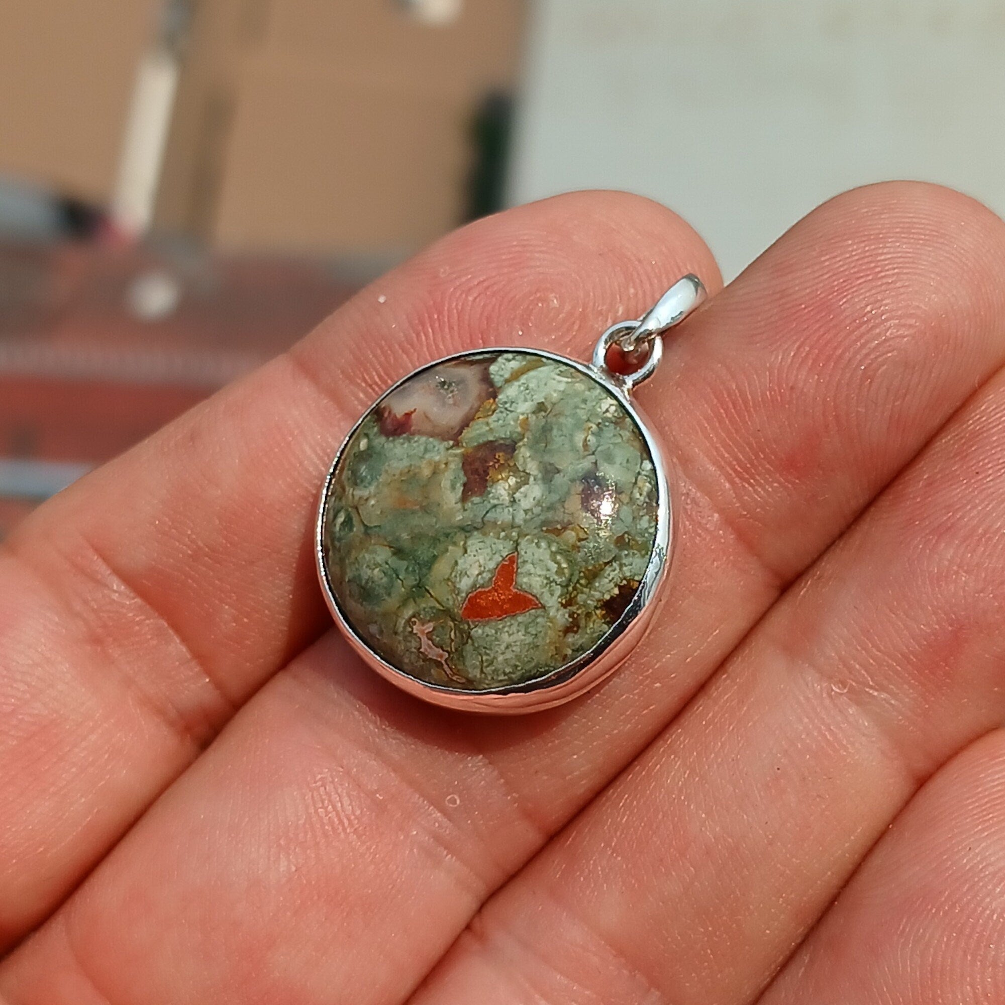 A beautiful round Green Jasper Pendant set in sterling silver, showcasing its minimalist design and vibrant color.