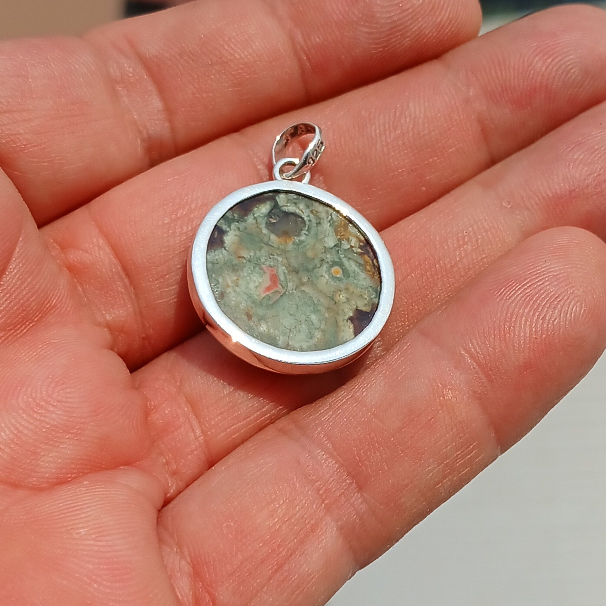 A beautiful round Green Jasper Pendant set in sterling silver, showcasing its minimalist design and vibrant color.