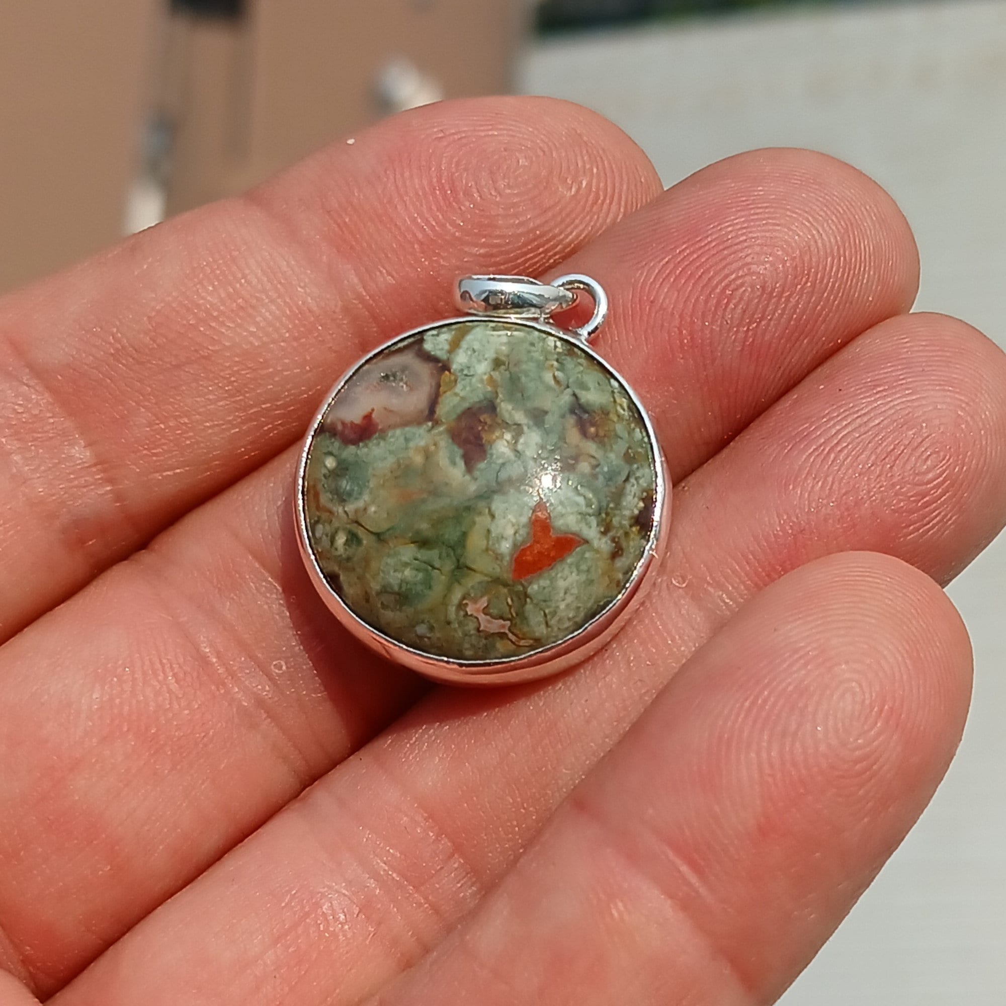 A beautiful round Green Jasper Pendant set in sterling silver, showcasing its minimalist design and vibrant color.