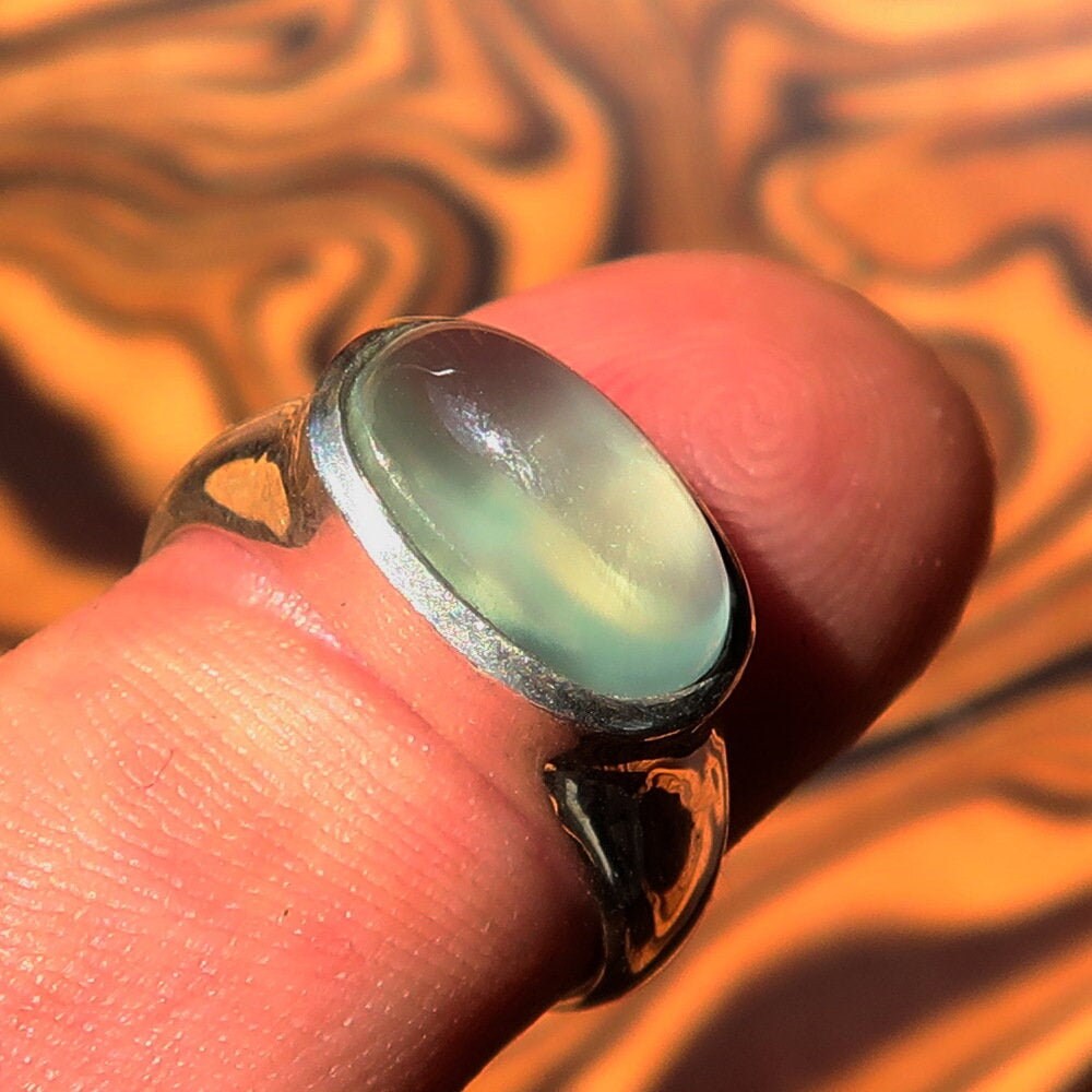 Handmade sterling silver solitaire ring featuring an oval green Prehnite stone, showcasing a polished finish and minimalist design.