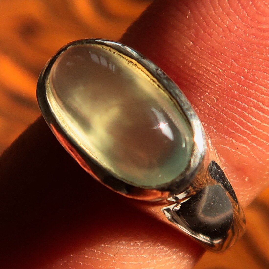 Handmade sterling silver solitaire ring featuring an oval green Prehnite stone, showcasing a polished finish and minimalist design.