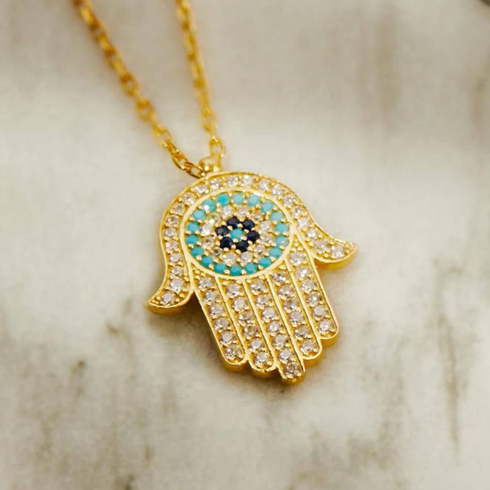 Hamsa Hand With Evil Eye Pendant Necklace in gold, featuring sparkling white and blue zircons.