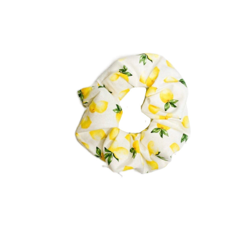 A fluffy lemon scrunchie made from soft fabric, perfect for all hair types, displayed against a neutral background.